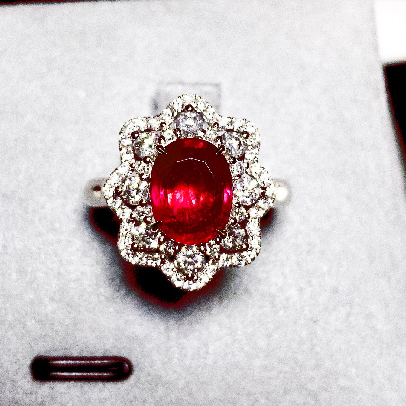 A Classical Ruby Cluster Ring in 18K White Gold. The Ruby is first surrounded by 8 larger round brilliant cut diamonds, followed by multi smaller Diamond pave. The larger Diamonds are giving off strong fire and brilliance while the smaller ones make