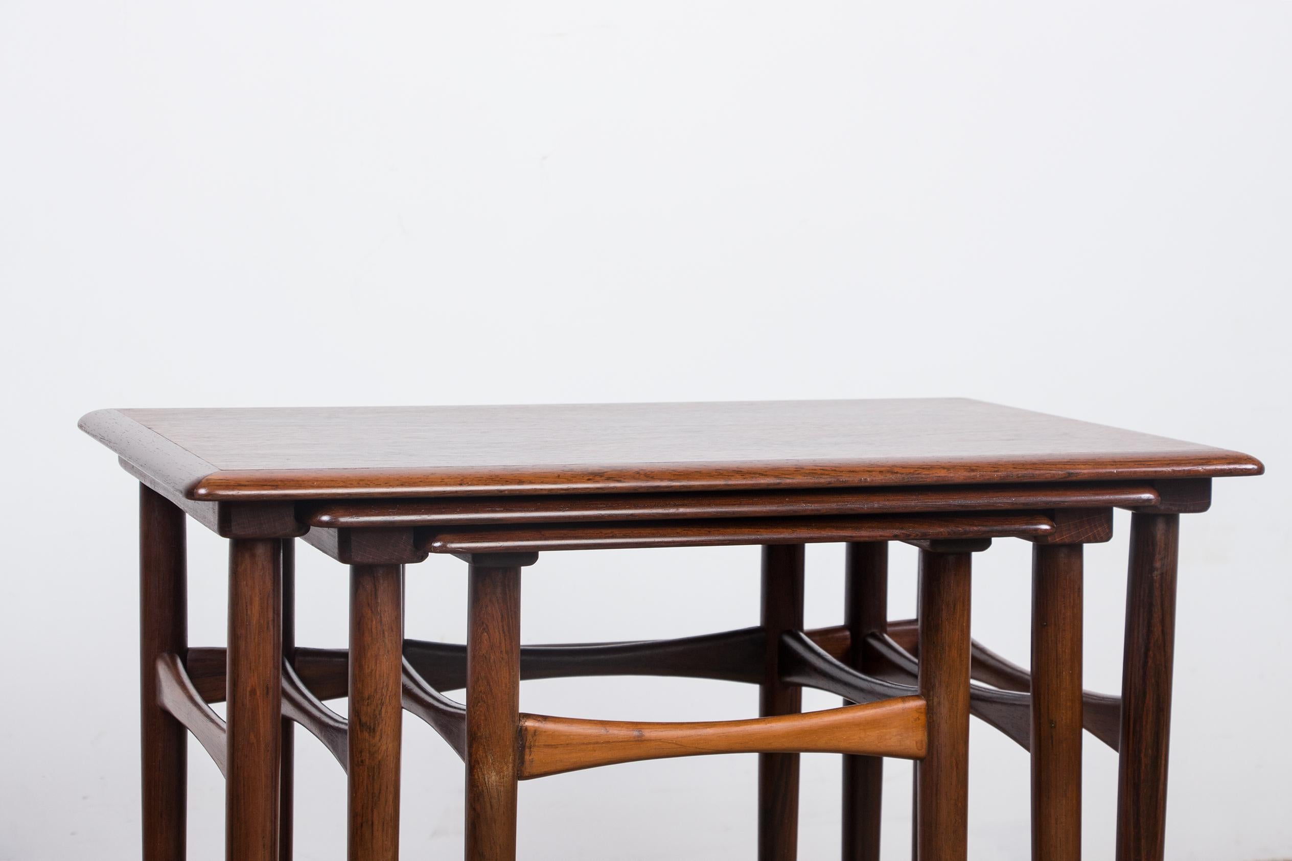 Magnificent nesting tables with legs and edges in solid Rosewood. They have a small inner rail that allows them to be embedded. Design of great finesse, manufacturing of very good quality.