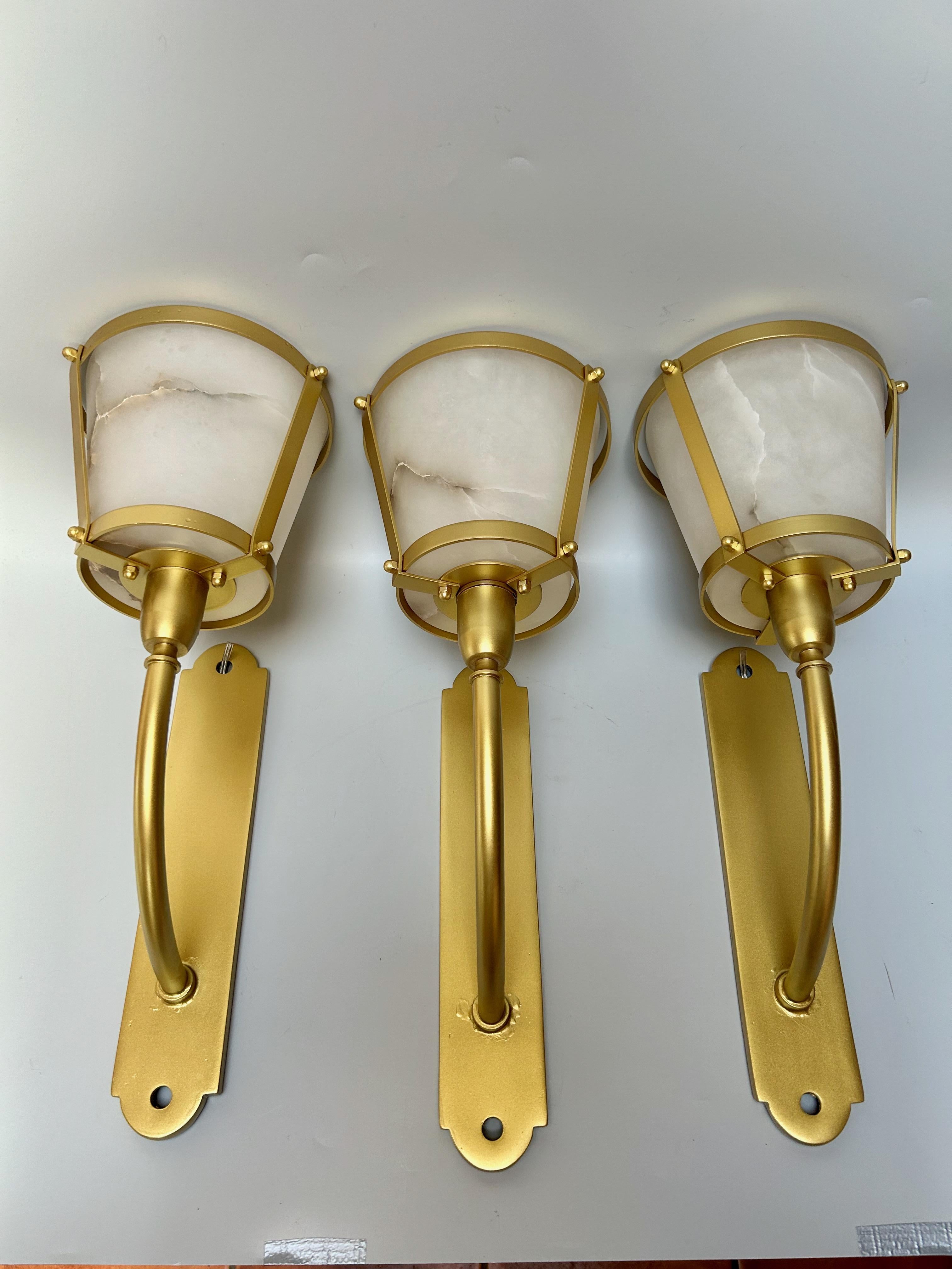 Ensemble de trois appliques en laiton doré, vers 1945.
Tulipes d'albâtre.
Electrifié et en parfait état.
Douille B22, ampoule à baïonnette.
La dorure a été refaite.

Hauteur : 39,5 cm
Largeur : 15 cm
Profondeur : 20 cm
Poids : 5.5 kg