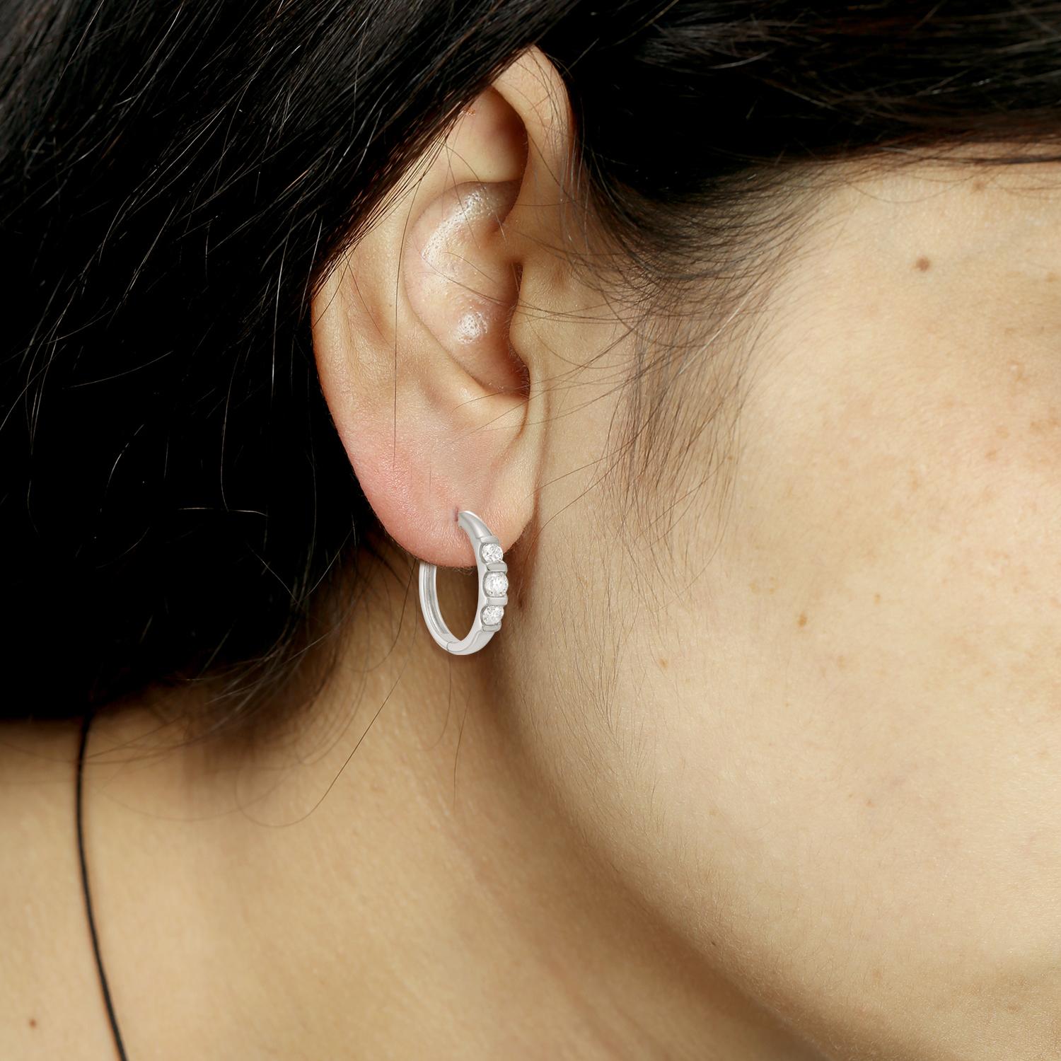 Atemporales con un toque moderno, estos pendientes de aro minimalistas presentan tres diamantes brillantes que suman 1,50 quilates, engastados en oro blanco pulido de 14 quilates. El diseño limpio y abierto ofrece la cantidad justa de brillo, ideal
