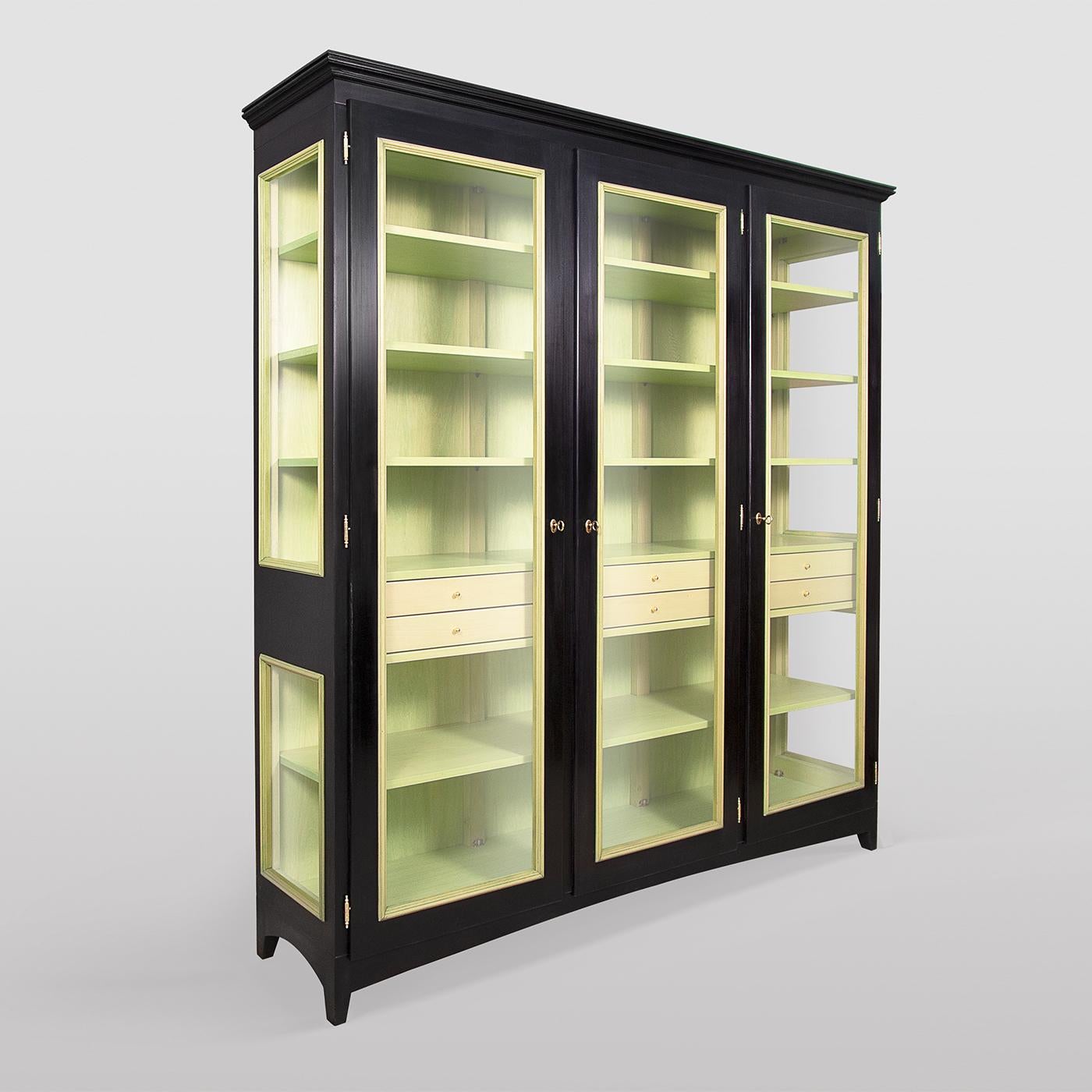 A showcase of well-balanced proportions and exquisite craftsmanship, this display cabinet has a solid lime wood frame with three glass doors equipped with double hook closing (upper and lower), each opening to reveal four shelves and two drawers.