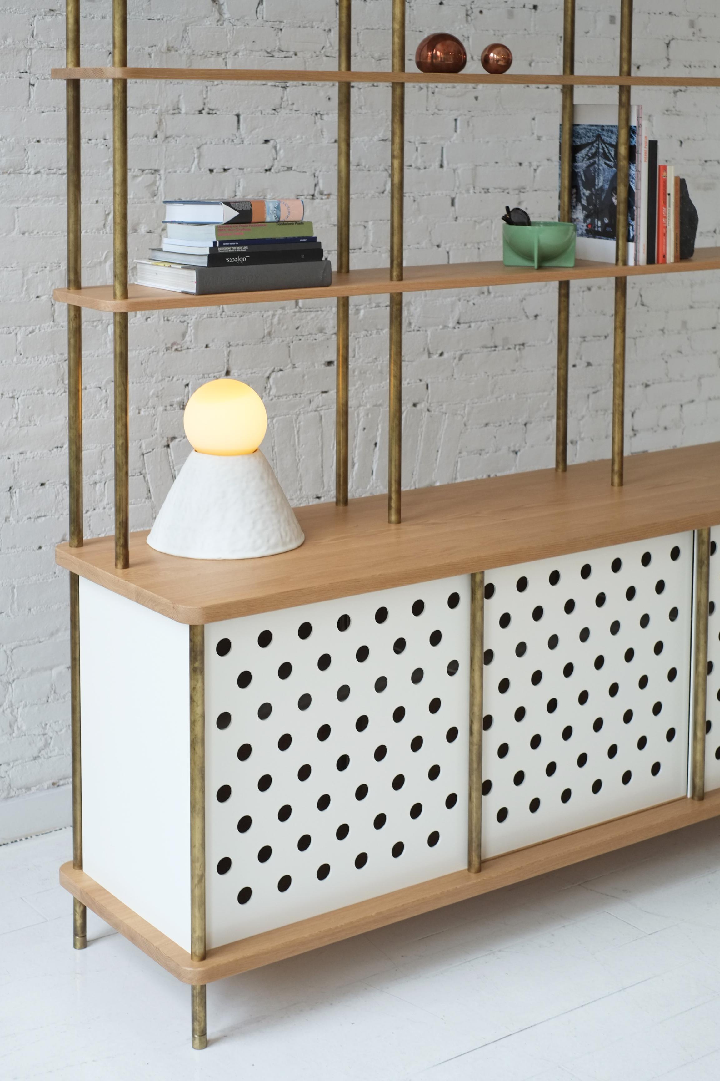 Consistent with the Strata collection, the new Strata sideboard is designed to be modular in order to create versatile configurations tailored to your needs. Shown with brass rods, walnut shelving and powder coated aluminum sliding doors, all