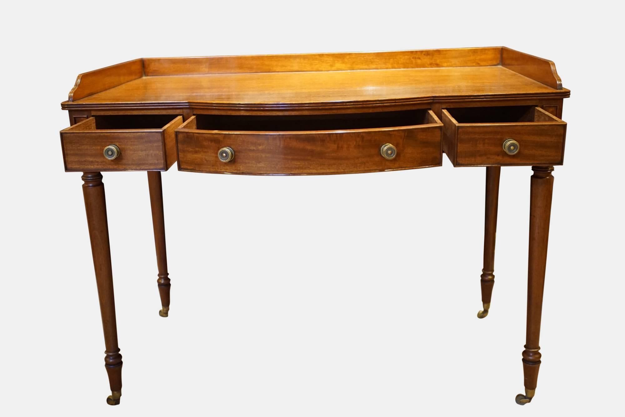 A 3-drawer mahogany side table with bow-fronted central drawer standing on finely turned legs, attributed to Gillows of Lancaster,

circa 1820.
