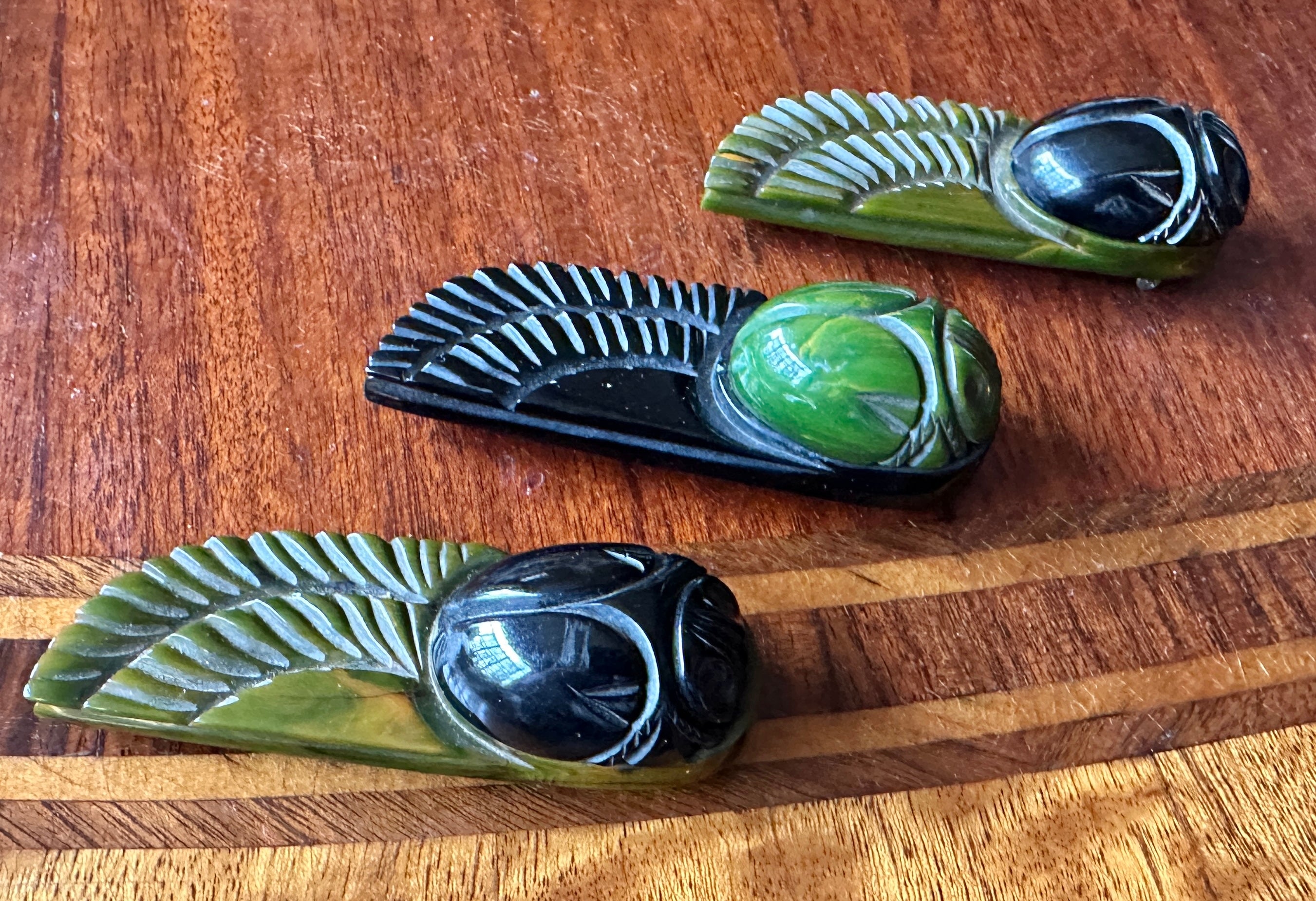 Indulge in a rare set of three Art Deco Egyptian Revival Winged Scarab Beetle Insect Dress Clip Brooches in Marbled Bakelite.   The Museum Quality brooches depict winged Scarab beetles, one of the signature motifs of the Egyptian Revival movement.