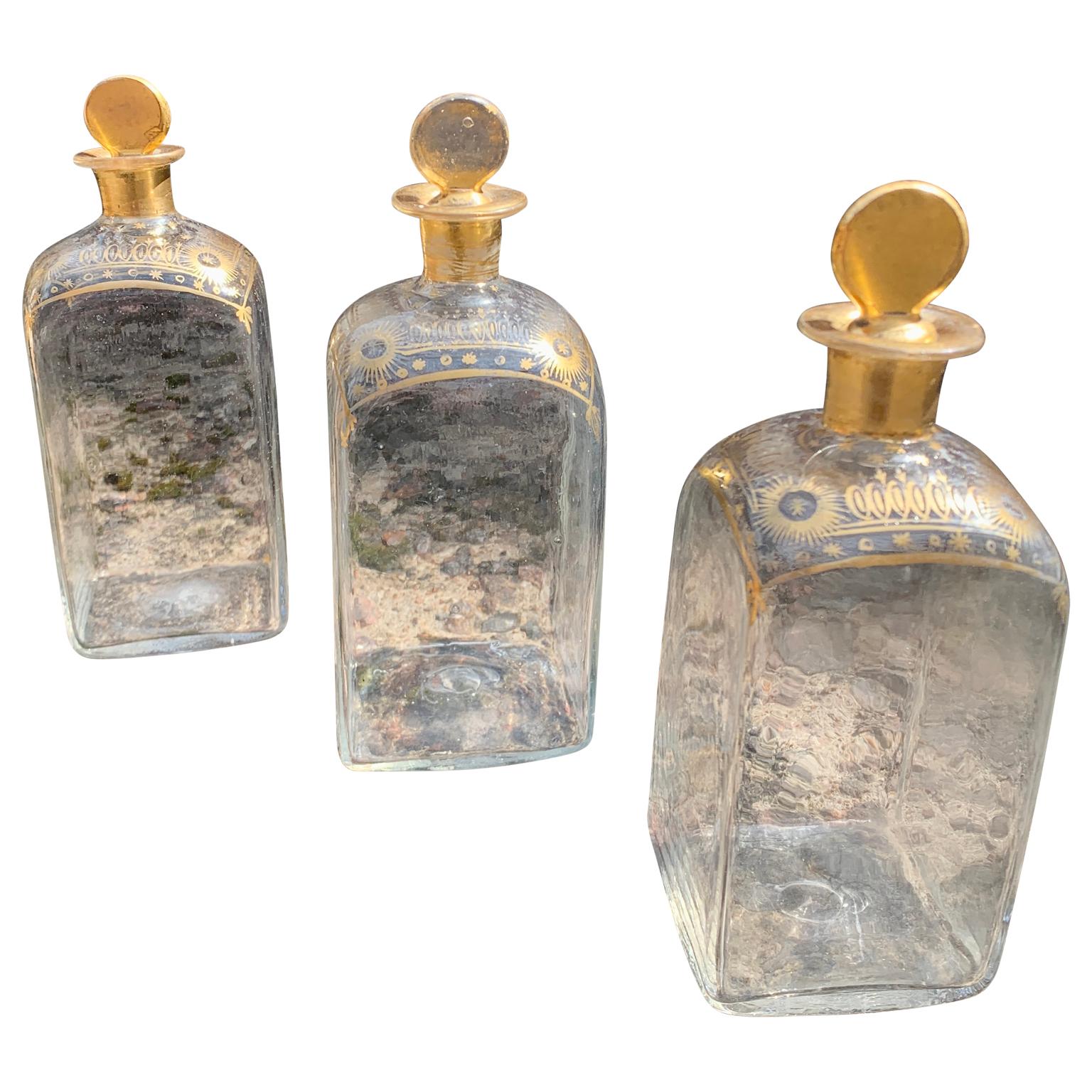 A set of three French hand made (hand blown) liquor decanters or bottles with the original glass corks. These French transparent glass and antique pieces from the very early part of the 19th Century, are hand-painted all around with gold enamel