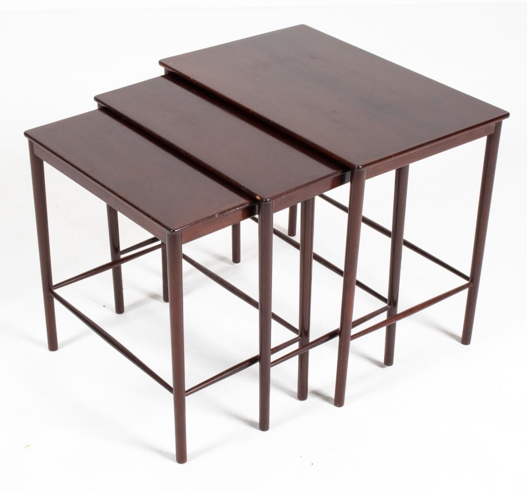 An attractive set of three Danish mid-century nesting tables designed by Grete Jalk for Poul Jeppesen, c. 1959. Featuring gently tapered legs with delicate stretcher bars, these petite-proportioned tables and their ability to nest with ease are