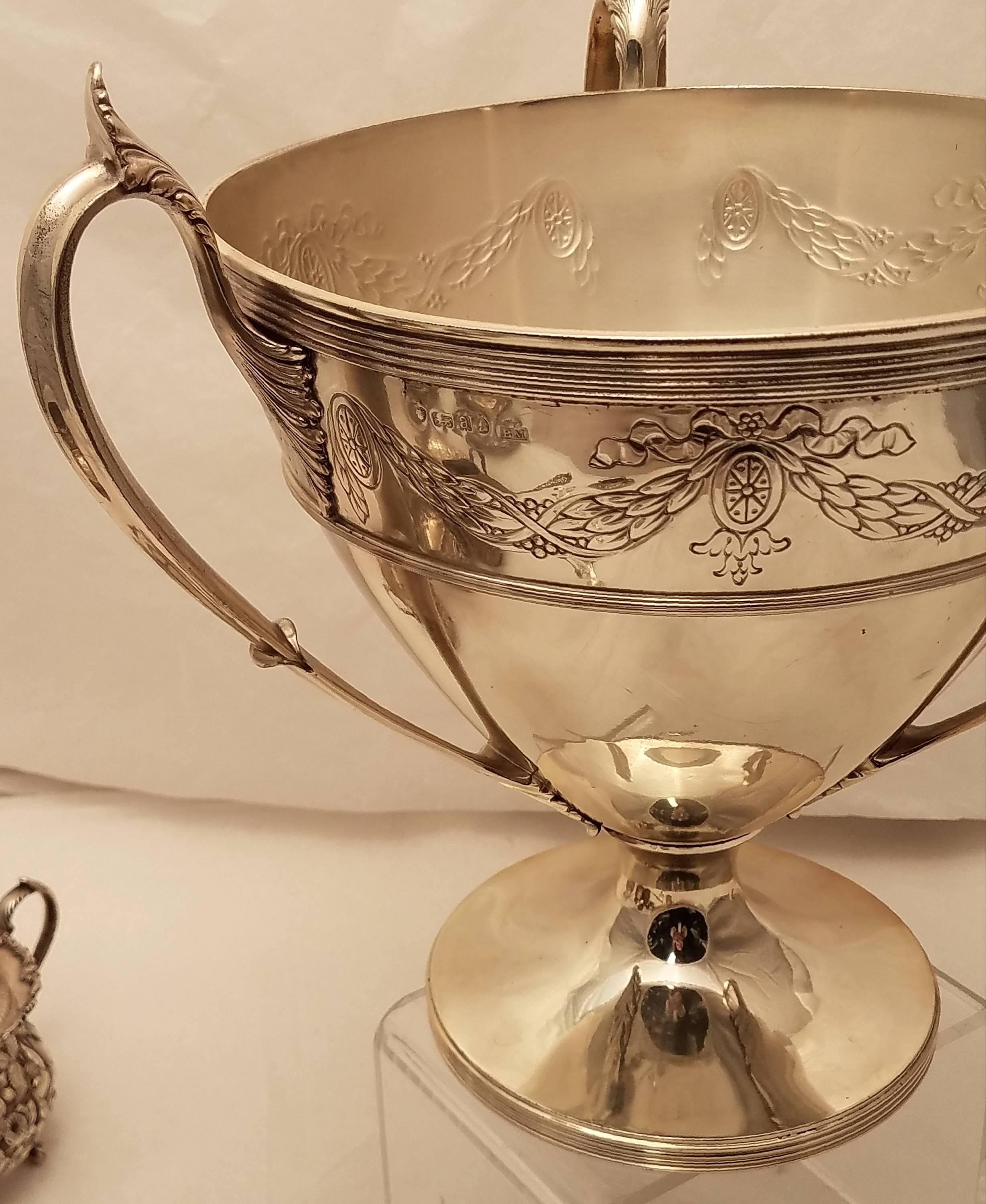 Magnificent English sterling silver three handled trophy with ornate design and leaf like pattern on handles, possibly by Berthold Muller, circa 1916. Weighing 48 troy ounces. Measuring 9.3 inches tall and 11 inches wide. Bearing hallmarks as shown