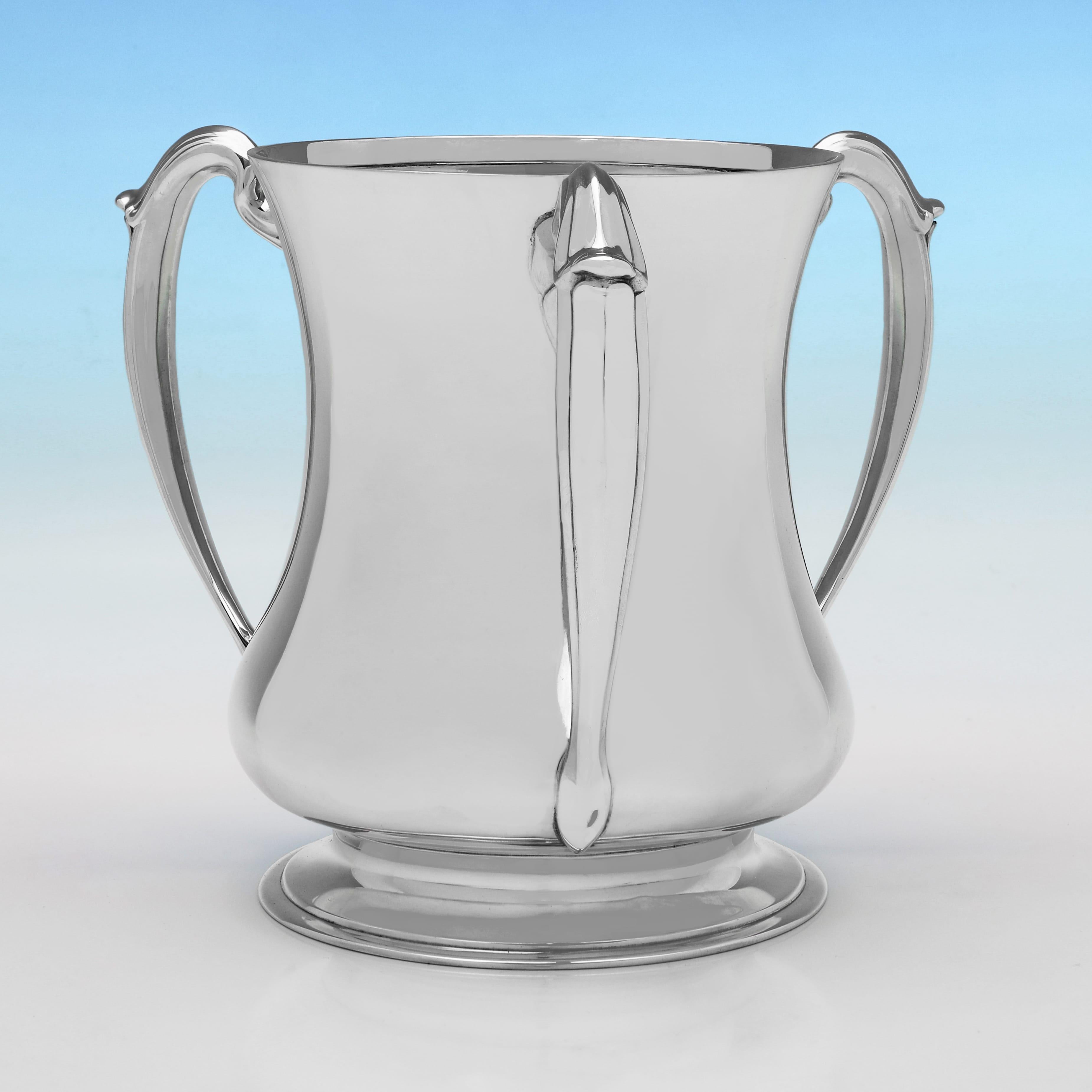 Marcada en Sheffield en 1925 por Henry Atkin, esta copa amorosa de plata de ley de la época de Jorge V tiene tres asas y un diseño sencillo. Sería un bonito enfriador de vino para una botella de champán. 

La taza mide 18 cm de altura, 20,5 cm de
