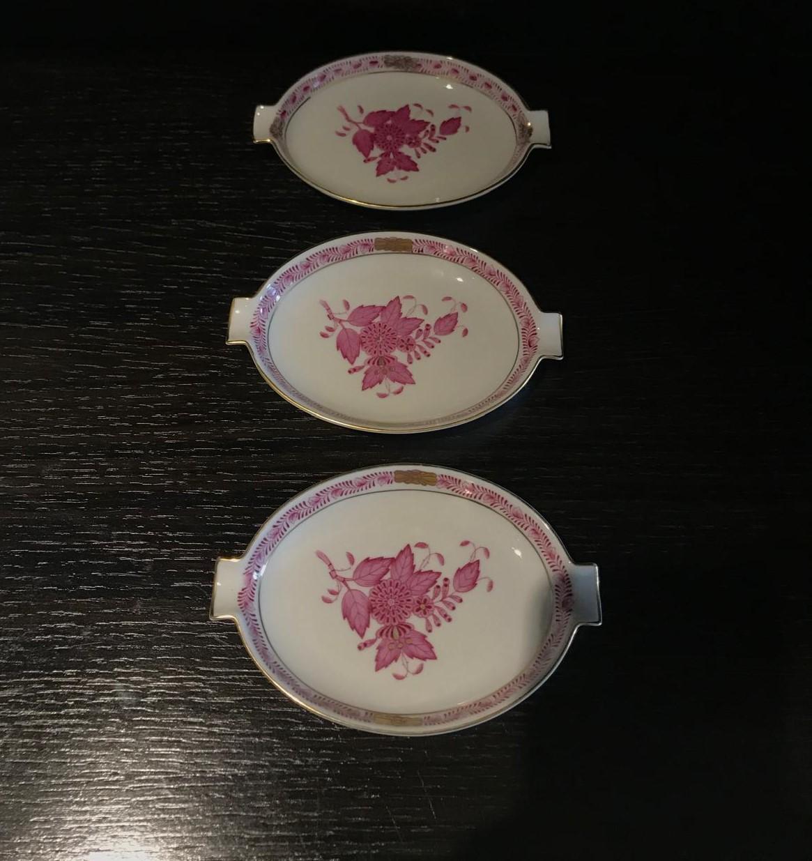 Presentamos a la venta un juego de tres hermosos platos ovalados pequeños de Herend de Hungría que pueden utilizarse como bandejas para alfileres, platos para anillos/joyas, bandejas para cenizas, platos para bombones o simplemente como una pieza de