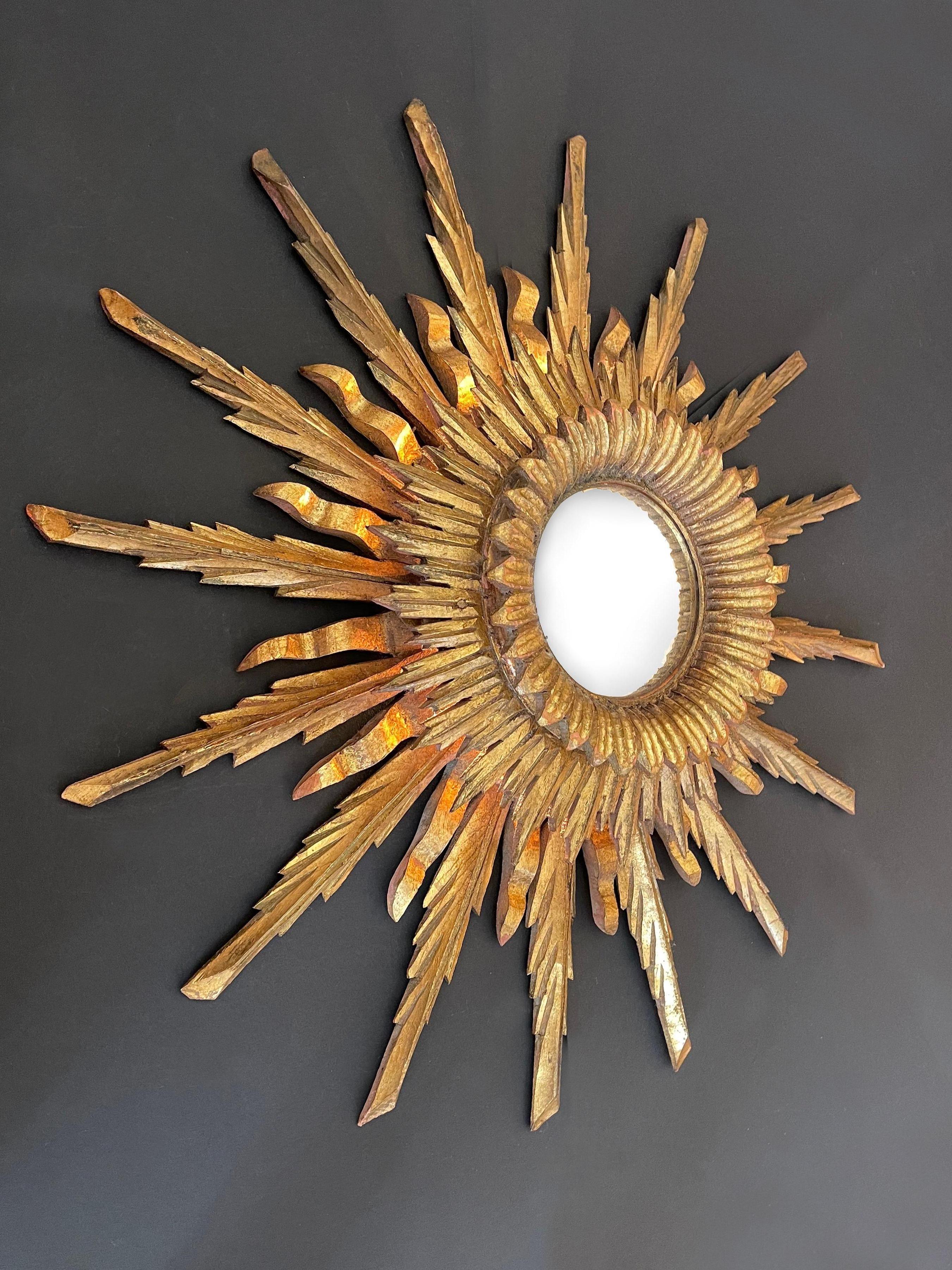 Impresionante espejo grande de madera dorada de 3 capas, con ''pétalos de sol'' retroiluminados y placa de espejo convexa.
La capa interior de rayos de sol bellamente tallados enmarca el espejo en forma de corona, casi floral.
Debajo de la capa