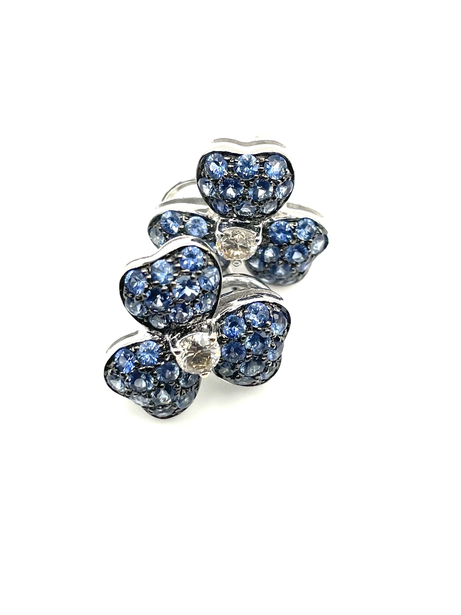 A pair of 18kt white gold 3 leaf clover earrings set with natural white diamonds and blue sapphires highlighted with a black rhodium finish straight post and omega clip system. Wear them everyday with any outfit.

60 natural blue sapphires 2.53ct