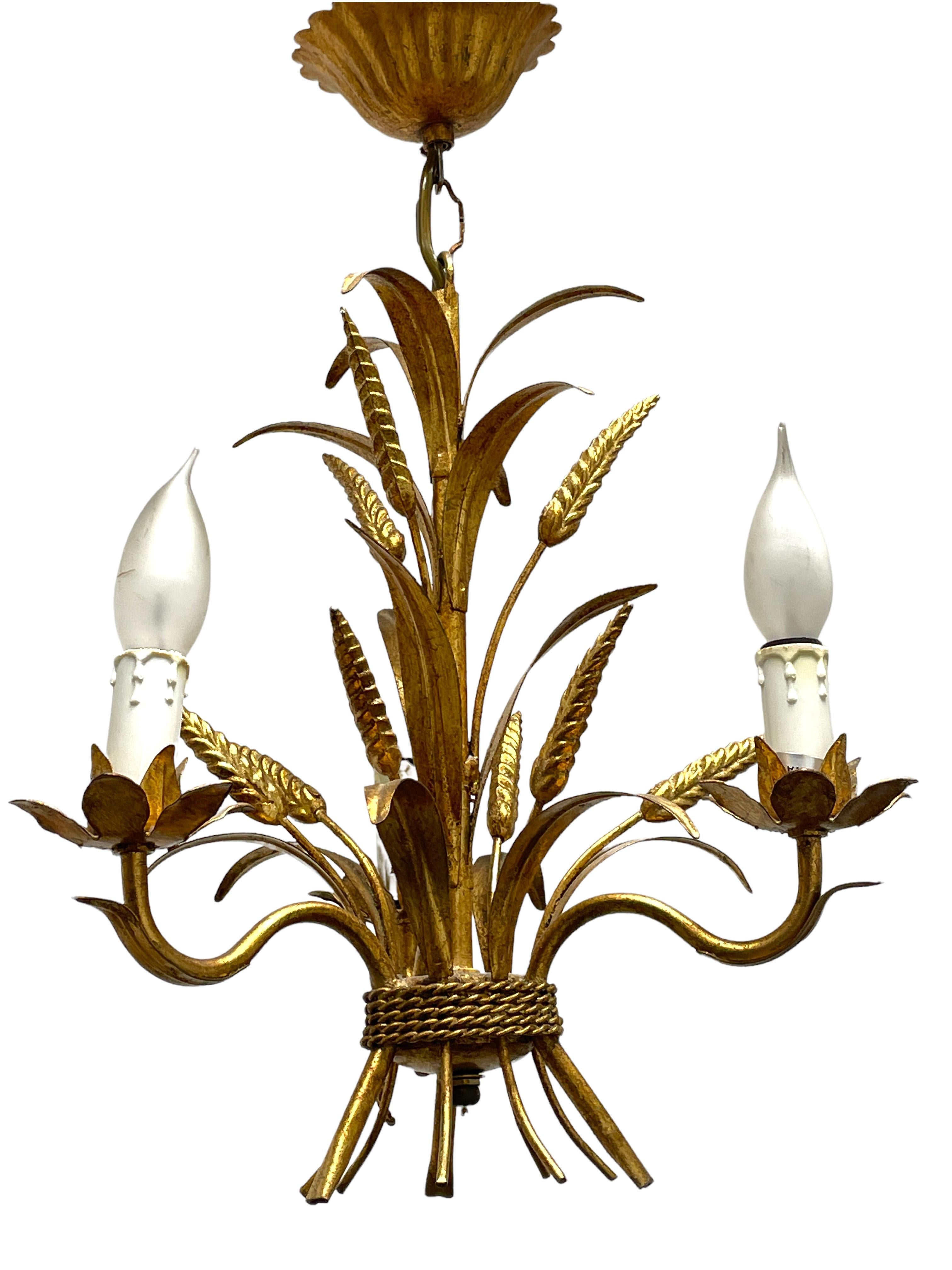 A Hollywood Regency midcentury gilt tole wheat sheaf chandelier in Coco Chanel Style, the fixture requires three European E14 candelabra bulbs, each bulb up to 40 watts. This light has a beautiful patina and gives each room an eclectic statement.