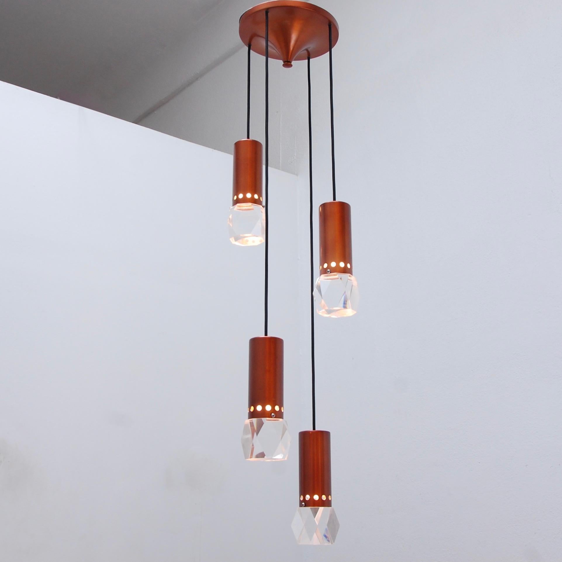 Three captivating pendant chandeliers with four pendant lights hanging from a single canopy in copper colored painted aluminum and Lucite shades, Italy, 1950s. Wired for use in the US. OAD can be adjusted upon request. Four E26 medium based light