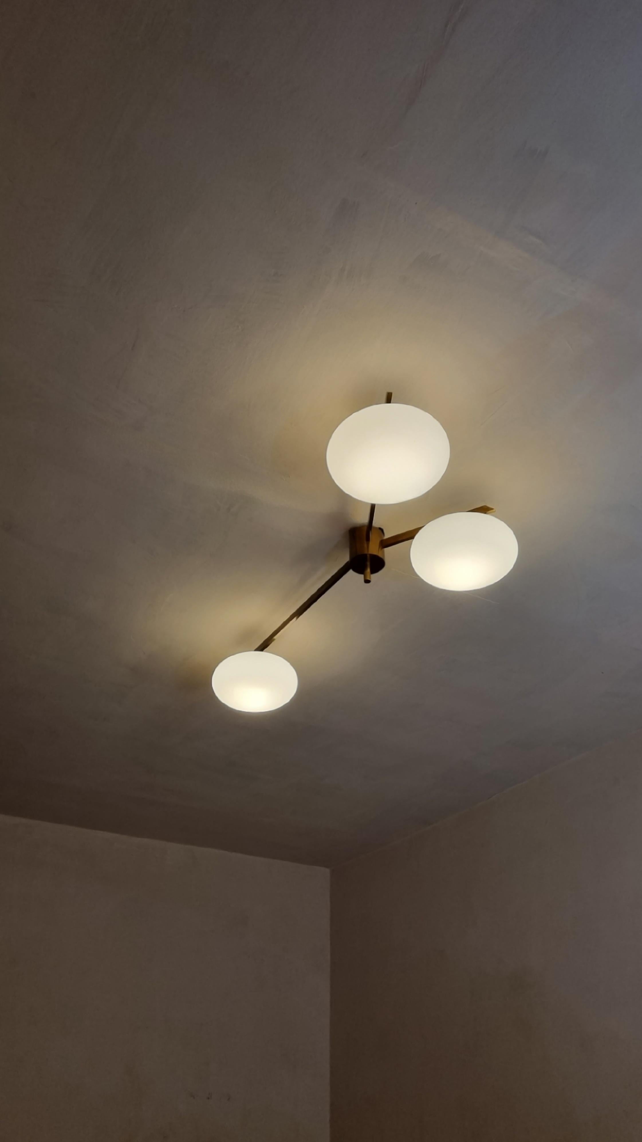 Lampada a soffitto 3 lune progettata nello stile di Angelo Lelii per Arredoluce.
Struttura in ottone, diffusori in vetro duplex opal bianco, 6 punti luce, eccellenti condizioni.

Questa lampada è stata concepita nello stile delle ben più famose e