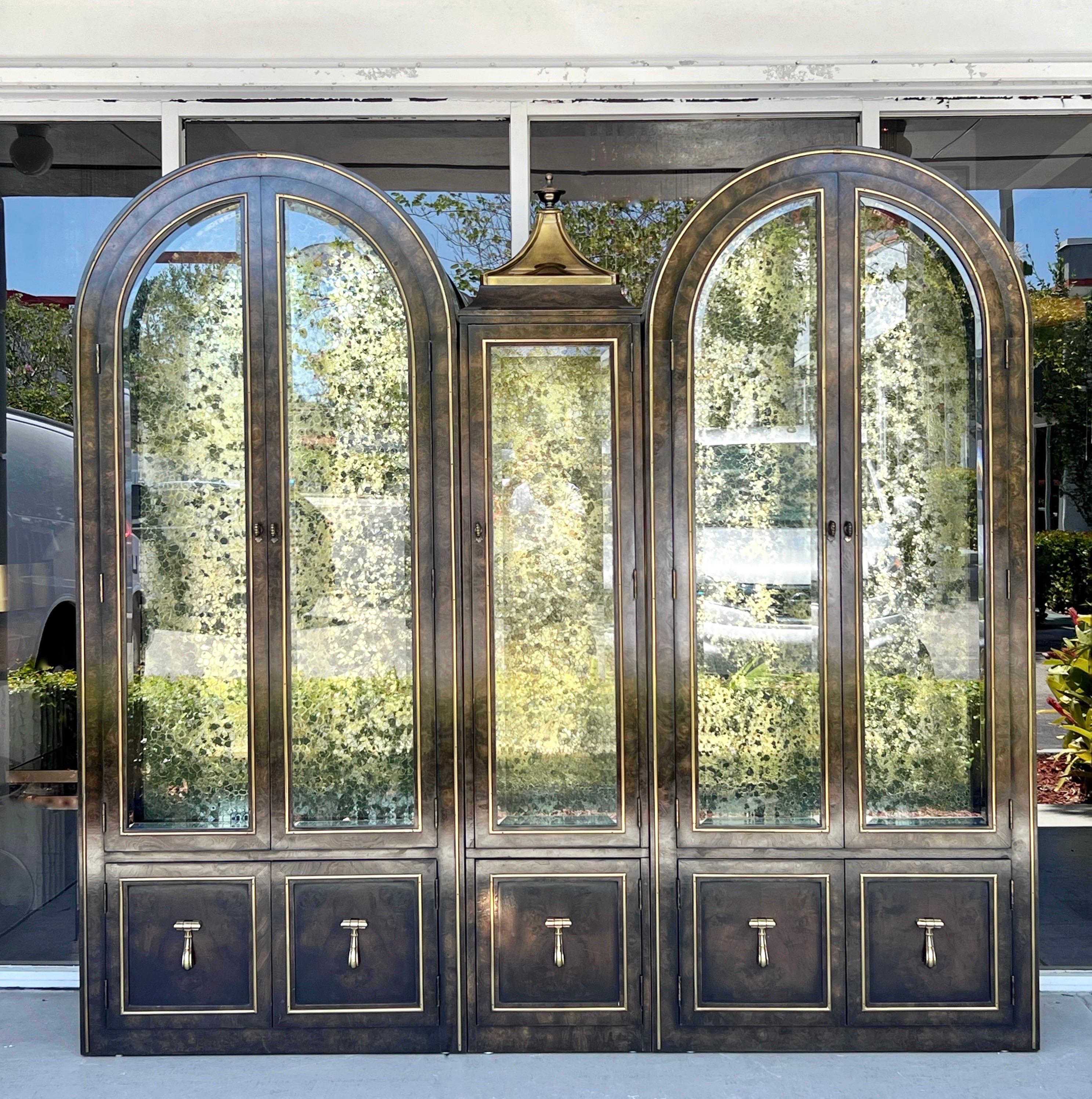 A set of William Doezema for Mastercraft display cabinets. Could be used individually as they are not attached to each other. All cabinets feature brass trim and beveled glass on front doors and sides, and large knocker style brass pulls on the