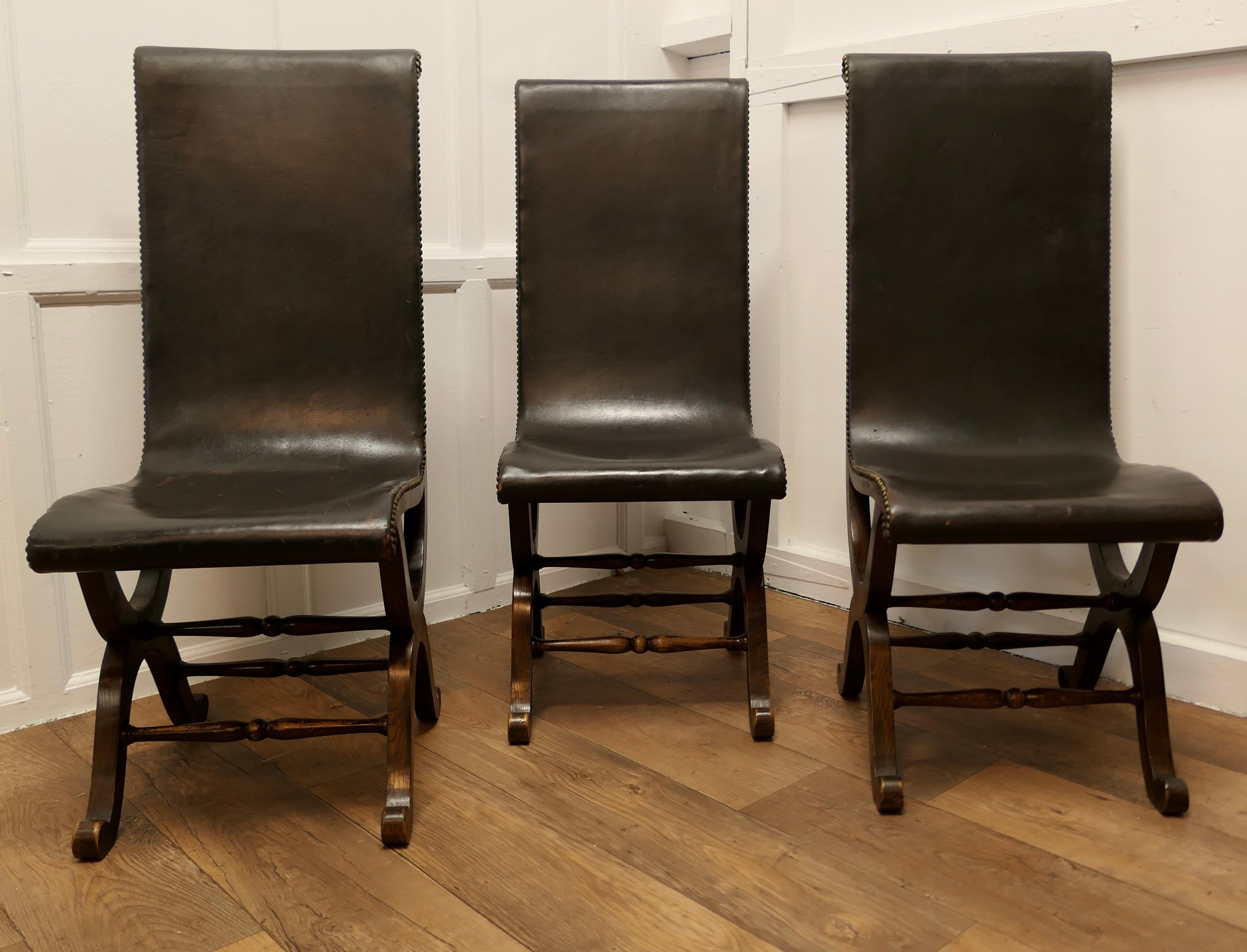 3 Matching midcentury Leather and Oak Fireside Sling Chairs by Pierre Lottier 

A Classic, the Slipper Chair, is in superb soft Black Leather hide on a Classic Neoclassical Oak X frame with brass stud work 
The chairs are 42” high, 16” wide