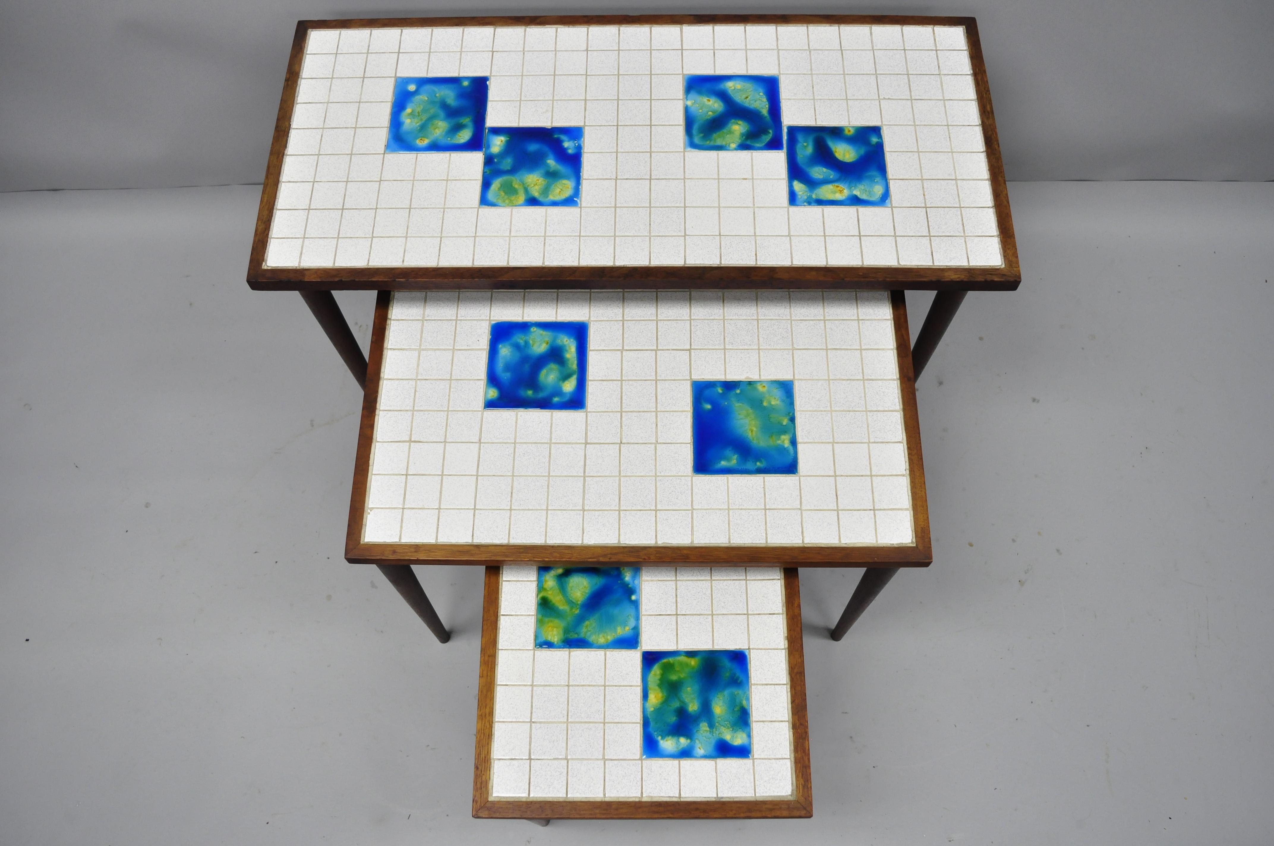 3 Mid-Century Modern Nesting Tile Top Tables Blue Green Tiles Danish Teak. Item features beautiful ceramic tops in white, green, and blue, 3 graduating sizes, teak tapered legs, and clean Modernist lines. Circa Mid 20th Century. Measurements: Large