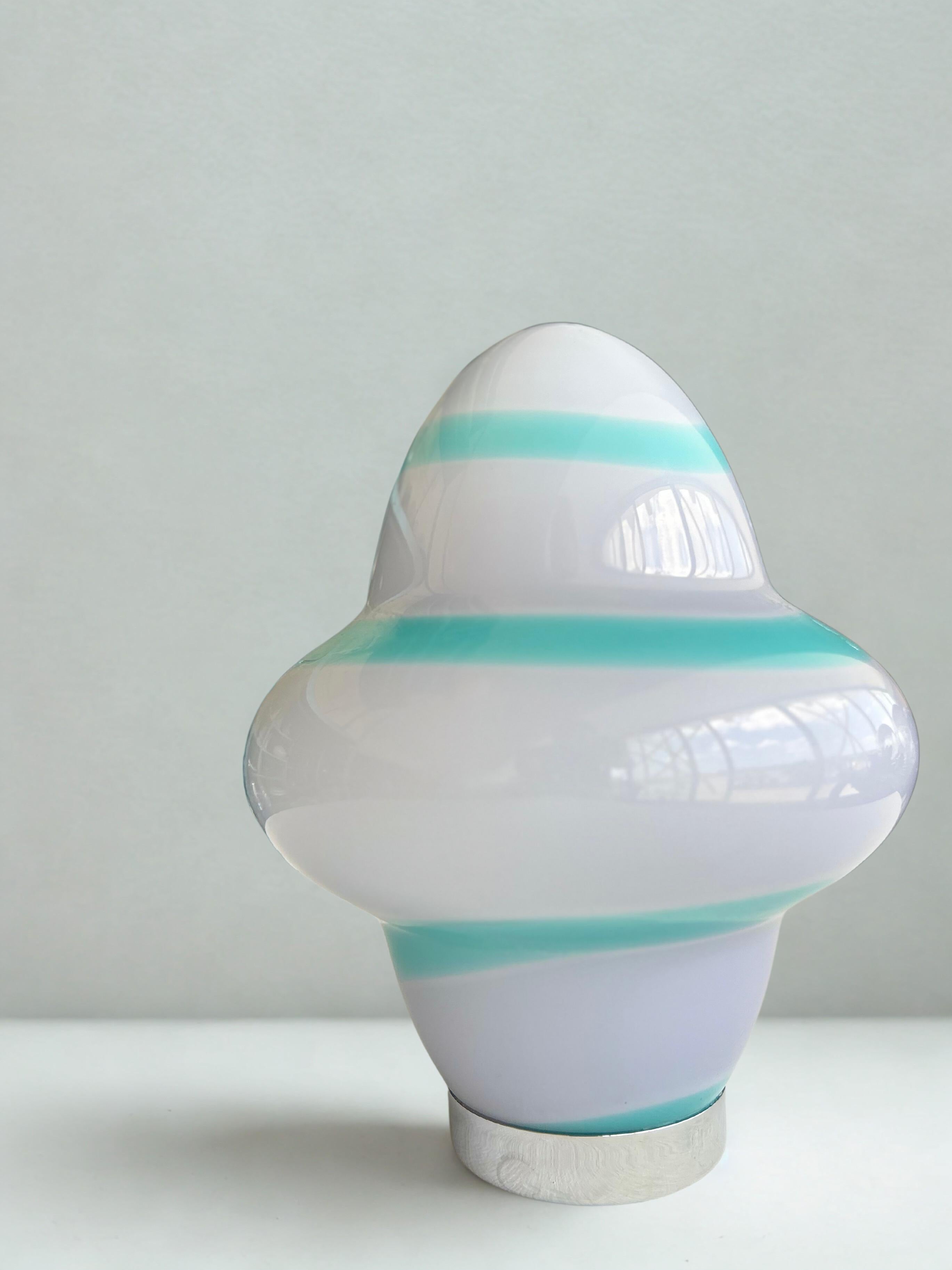 Magnifique lampe de table en verre soufflé à la main de Murano, blanc et bleu.
Conçue par Ettore Sottsass pour Venini et fabriquée en 1994.
L'abat-jour en verre est signé 
