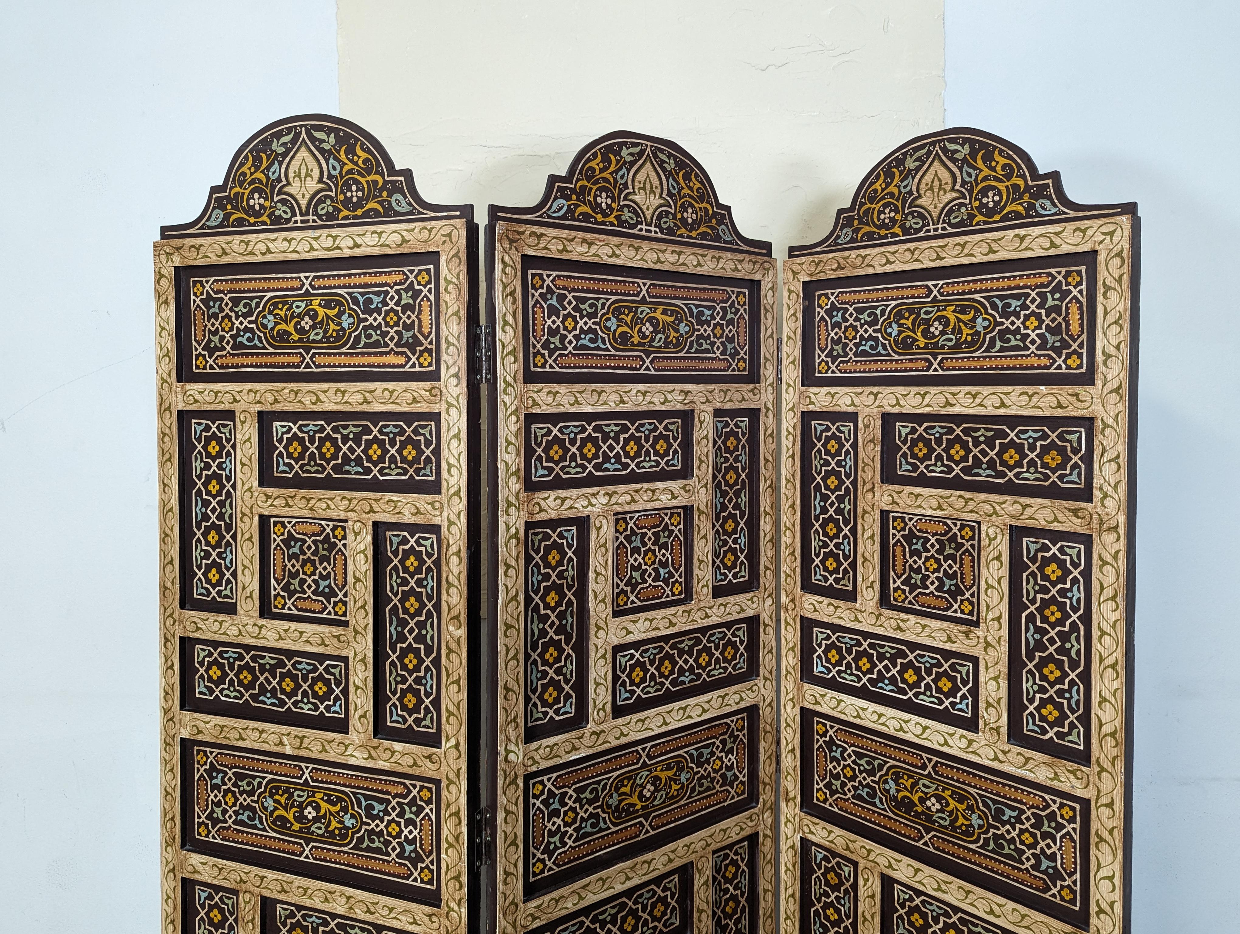 Step into the realm of vintage charm and distinctive style with this exquisite room divider, a piece that exudes the mysterious allure of a Moroccan bazaar or a Mediterranean villa. Spanning a total width of 57 inches, this three-panelled beauty