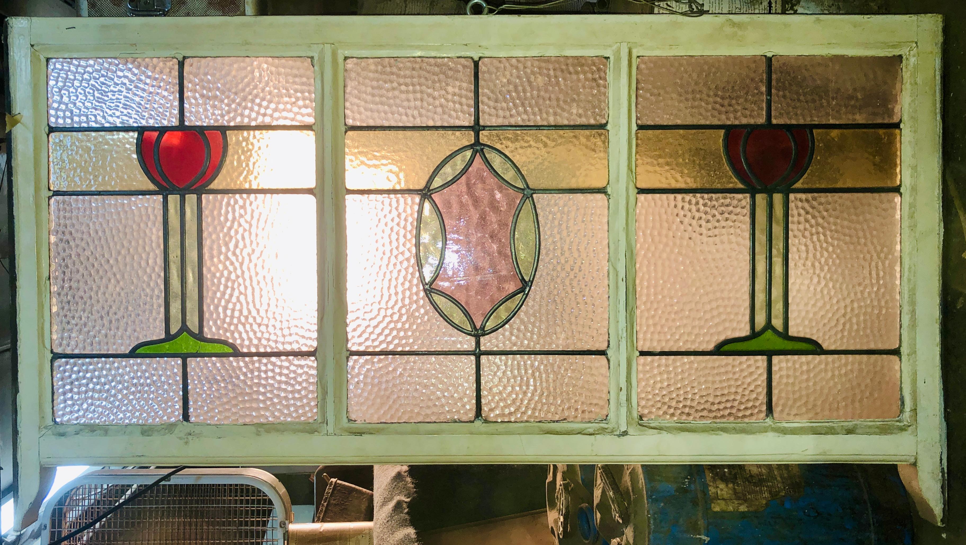 Esta ventana o travesaño tiene tres paneles, cada uno con diseños de cristal texturizado y coloreado. El centro es un adorno de color claro con dos rosas a cada lado.
Las dimensiones totales corresponden a la vidriera y el marco.
Situado en NY