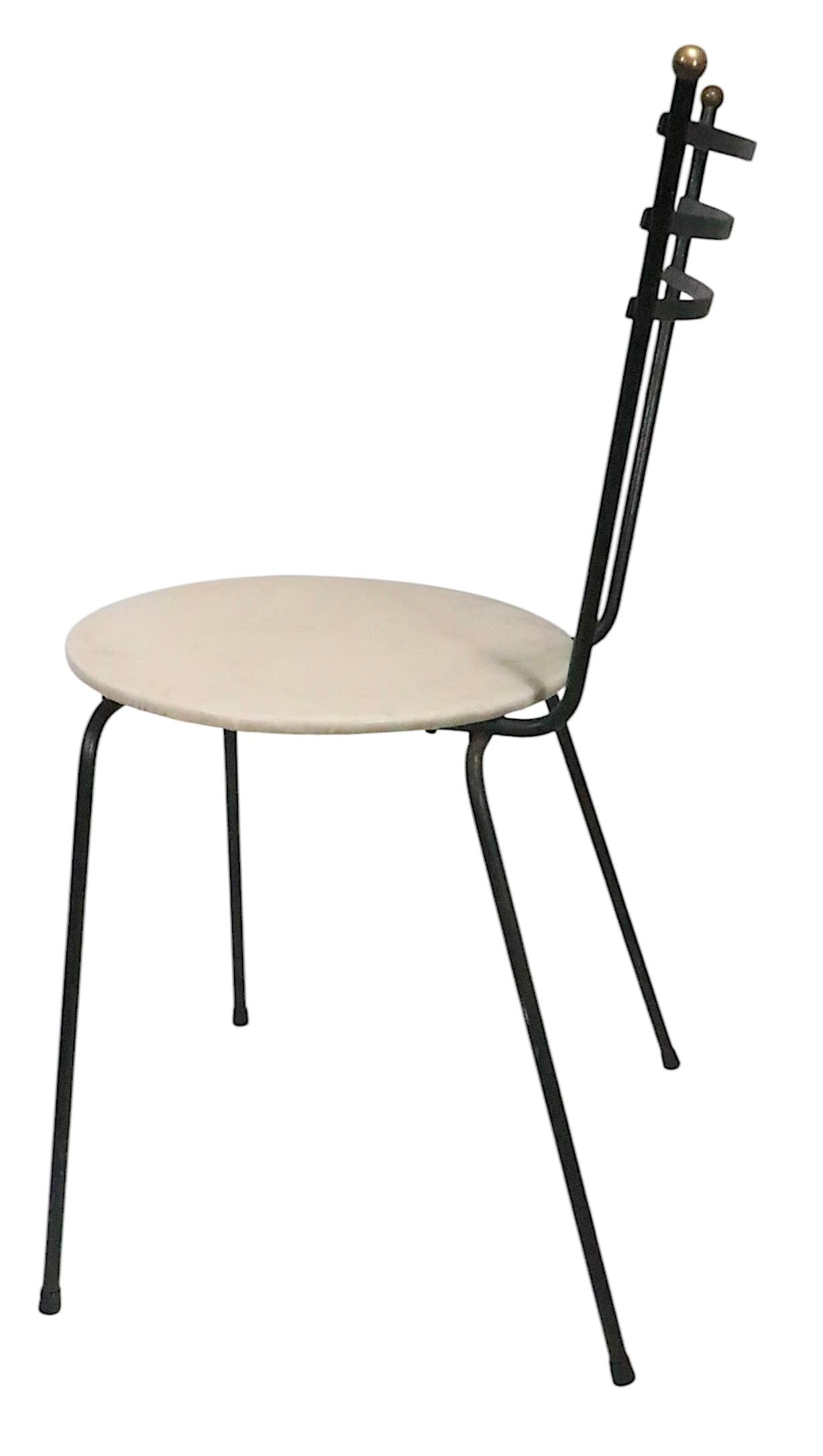 Clásico juego de mesa y sillas estilo comedor, cocina, bistró o cafetería de mediados de siglo, que incluye dos sillas y una mesa. Las sillas tienen armazón de hierro forjado, remates de bola de latón y asientos acolchados. La mesa de comedor estilo