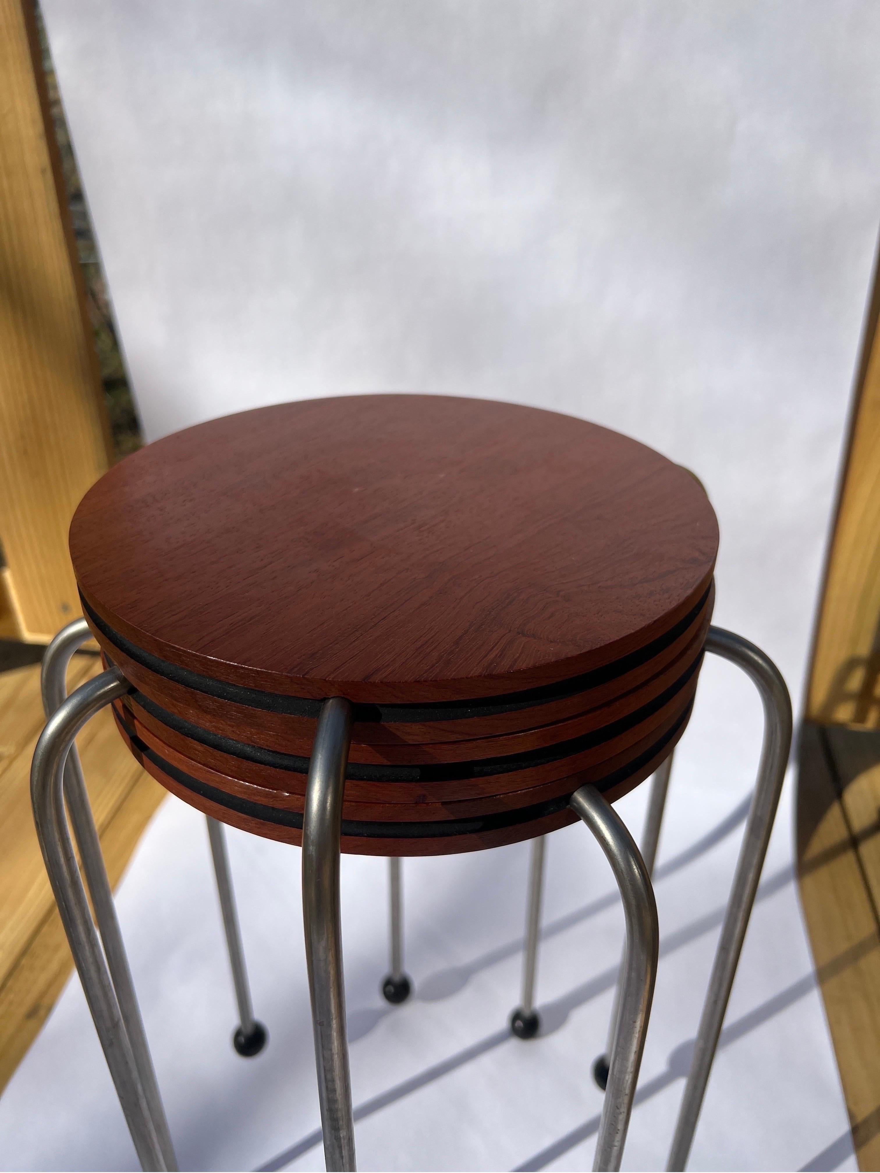 Set of 3 midcentury nesting tables constructed with round exotic wood tops, chrome legs and black ball feet. No apparent marks.