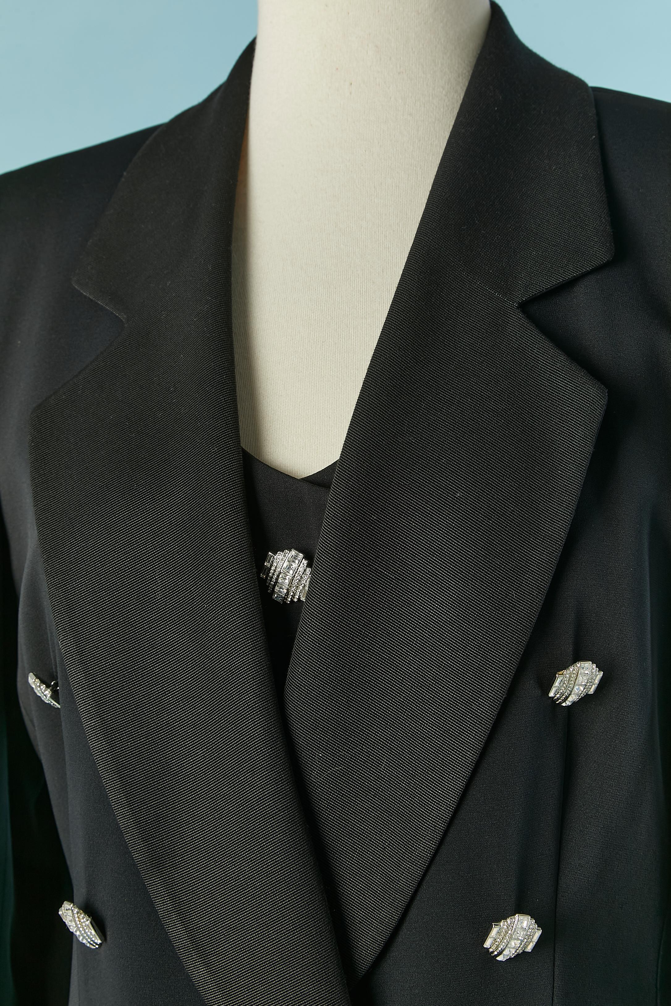 Tuxedo noir 3 pièces (veste, gilet et pantalon) avec boutons en strass. Composition du tissu principal : 62% acétate, 38% rayonne. Composition de la doublure : 100% rayonne. 
Pad d'épaule. Poche sur les deux côtés (veste et pantalon) 
TAILLE 42