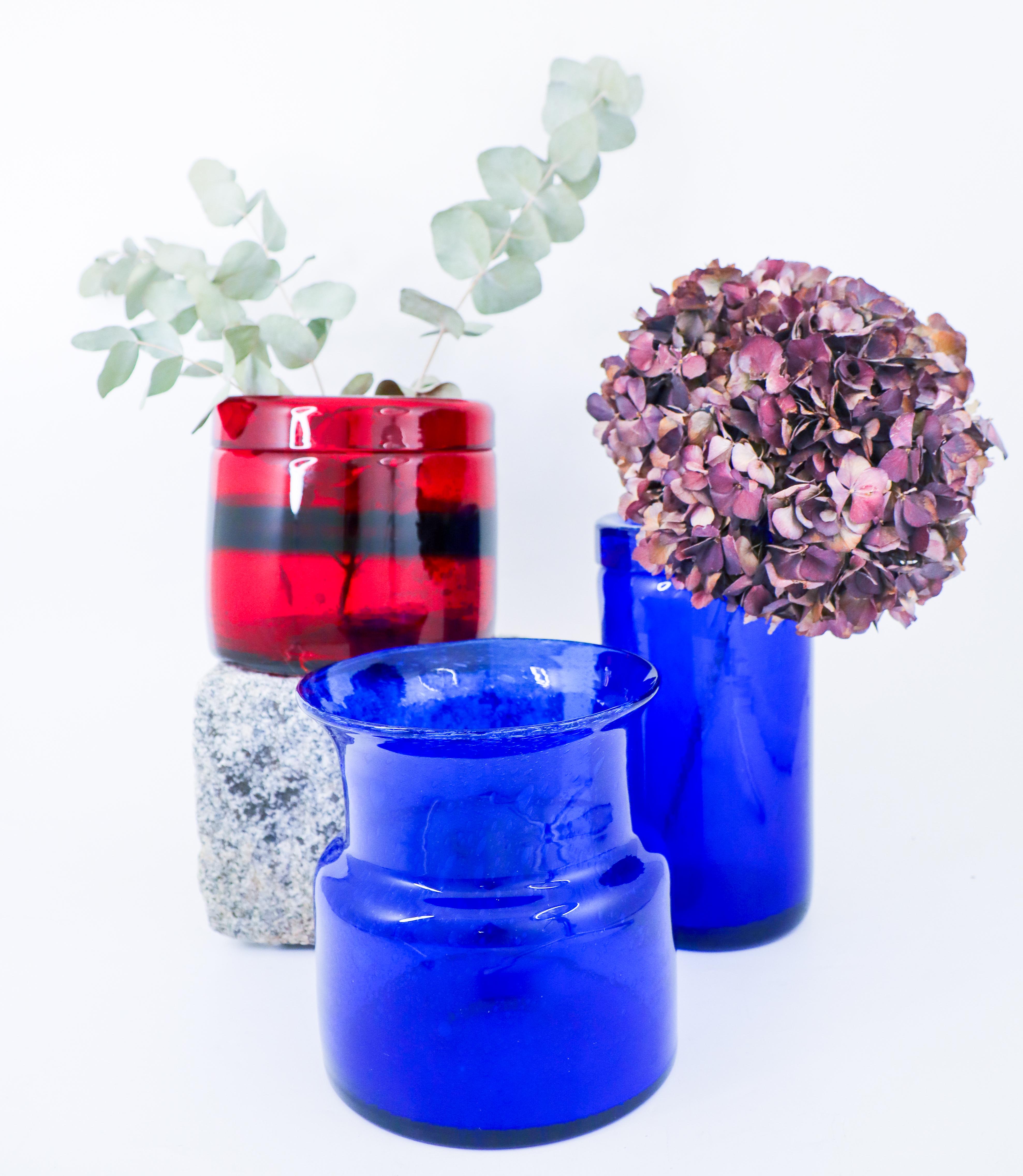 Drei Glasvasen, entworfen von Erik Höglund bei Boda, Schweden. Die rote Vase ist 13,5 cm hoch und hat einen Durchmesser von 15 cm, die höchste blaue Vase ist 21,5 cm hoch und hat einen Durchmesser von 11 cm, die andere blaue Vase ist 16,5 cm hoch