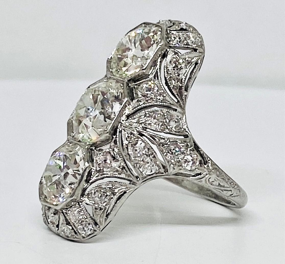 Creatively designed art deco style cocktail ring in platinum featuring 3 round cut white diamonds each in an octagonal milgrain beaded setting with center diamond weighing 2.00 carats set between 2 1.75 carat diamonds all with I color and VS