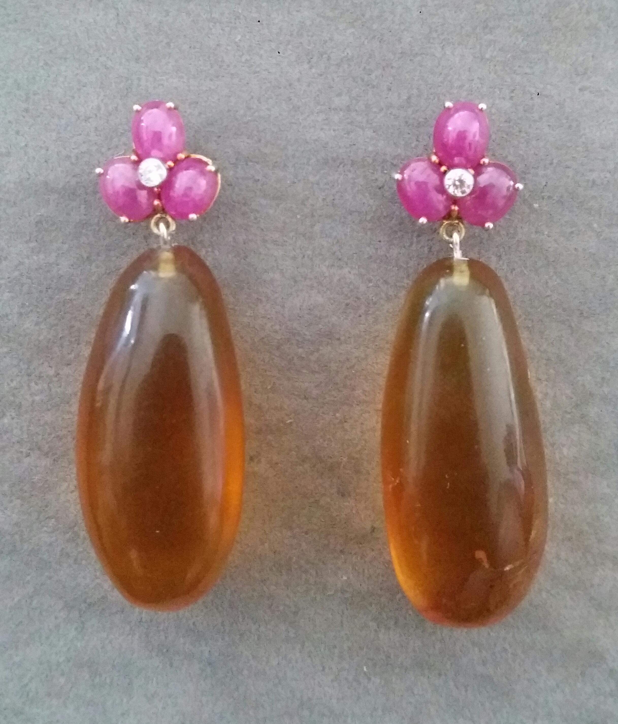 Elegant and completely handmade Earrings consisting of an upper part of 3 oval shape Ruby cabs of 4 mm x 5 mm set together in 14 Kt yellow gold with 2 small diamonds in the center, at the bottom 2 nice Pear Shape Natural Burmese Honey Amber 