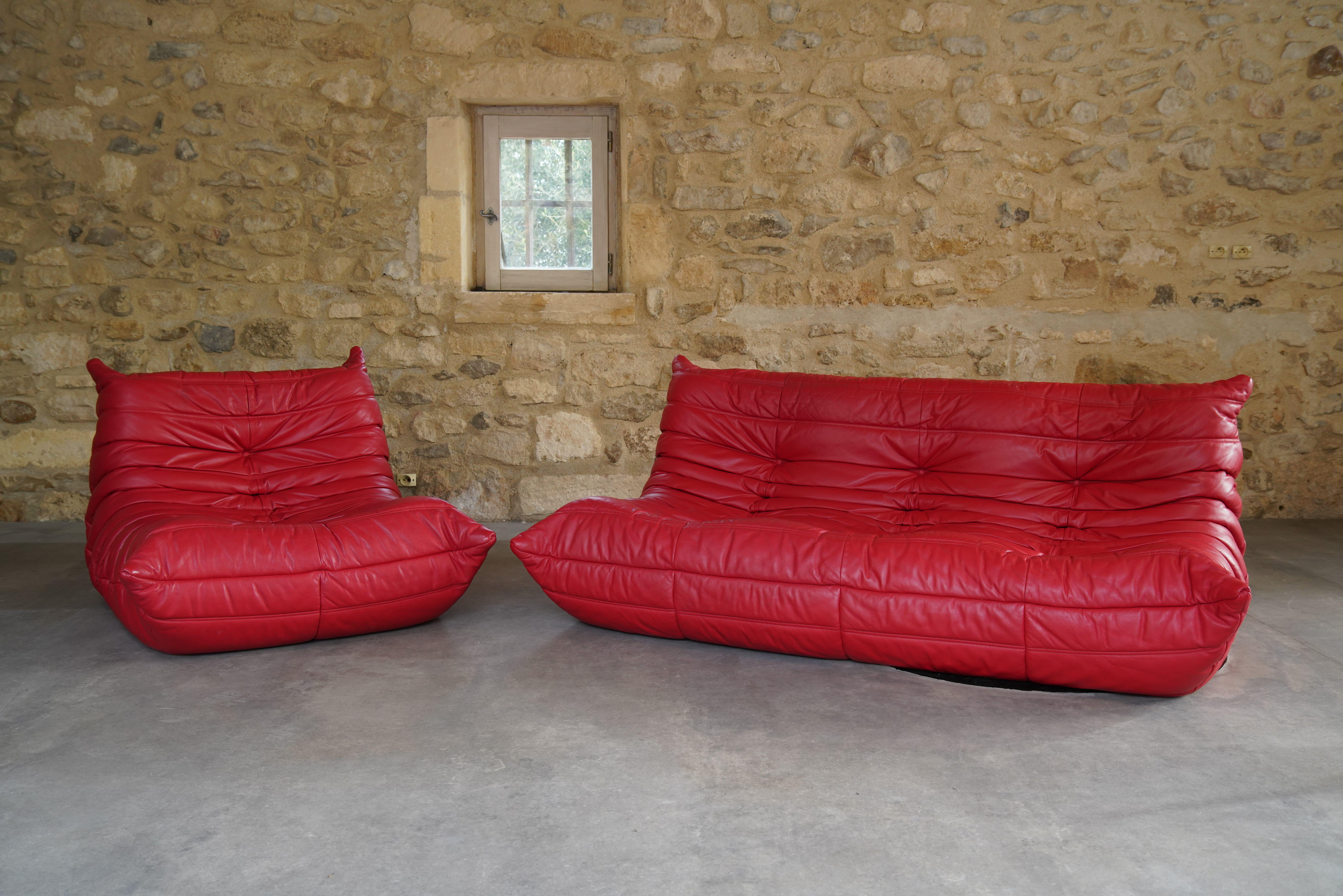 Beautiful red leather Togo three-seater sofa and chair designed by Michel Ducaroy for Ligne Roset from 2007.

Designer Michel Ducaroy drew inspiration for the Togo's design from an aluminum toothpaste tube noticing it “folded back on itself like a