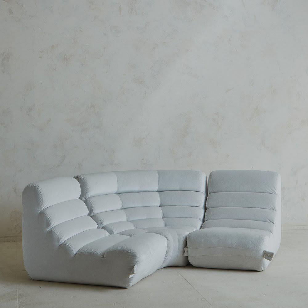 A three-section curved sofa featuring ribbed detailing and a sculptural shape reminiscent of designs by Michel Ducaroy. Low slung, ultra comfy and ready for a kitchen banquette, living room or lounge area. This piece has three buttons on the back