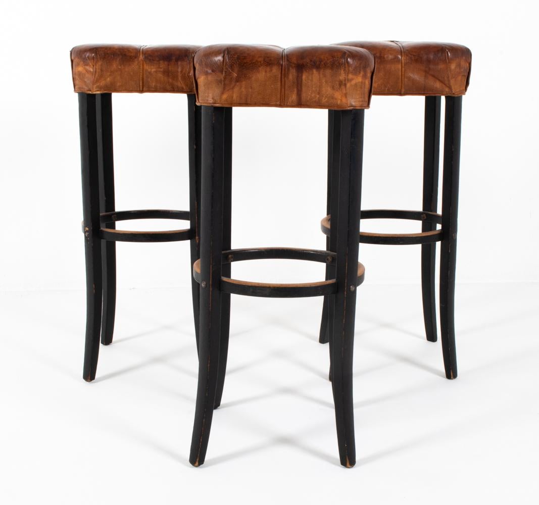 This set of (3) Art Deco stools have a dignified air about them, a lasting remnant of the time when they were made nearly a century ago. With subtly flared beech carved legs in a manner not dissimilar to Michael Thonet, these stools strike a neat