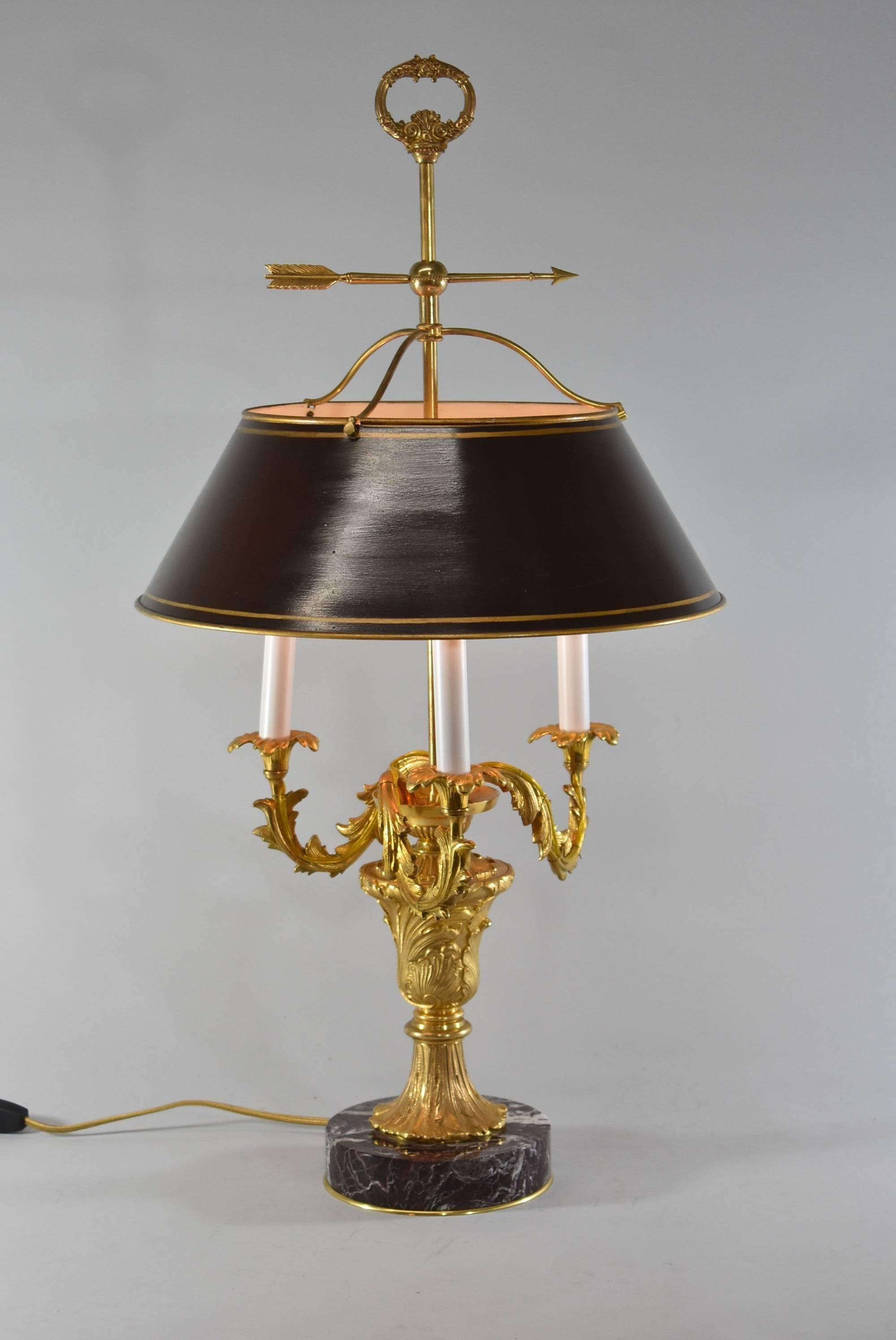 A French style bouillotte desk lamp. This beautiful lamp features a burgundy marble base, an adjustable brown tole shade with gold trim, three candelabra base sockets with leaf and floral form arms and a round floral finial. The dimensions of the