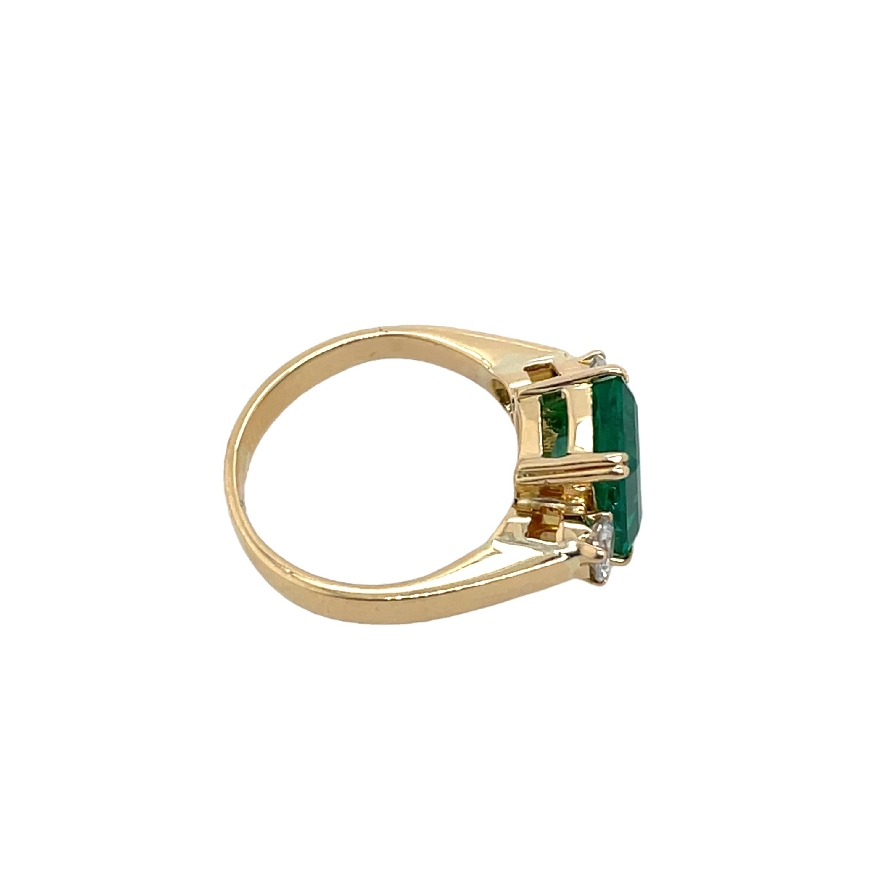 Ein klassischer Ring mit 3 Steinen aus 18 Karat Gelbgold, 
mit einem leuchtenden Smaragd, flankiert von zwei funkelnden runden Diamanten. Dieses elegante Design symbolisiert Vergangenheit, Gegenwart und Zukunft und eignet sich für jeden besonderen
