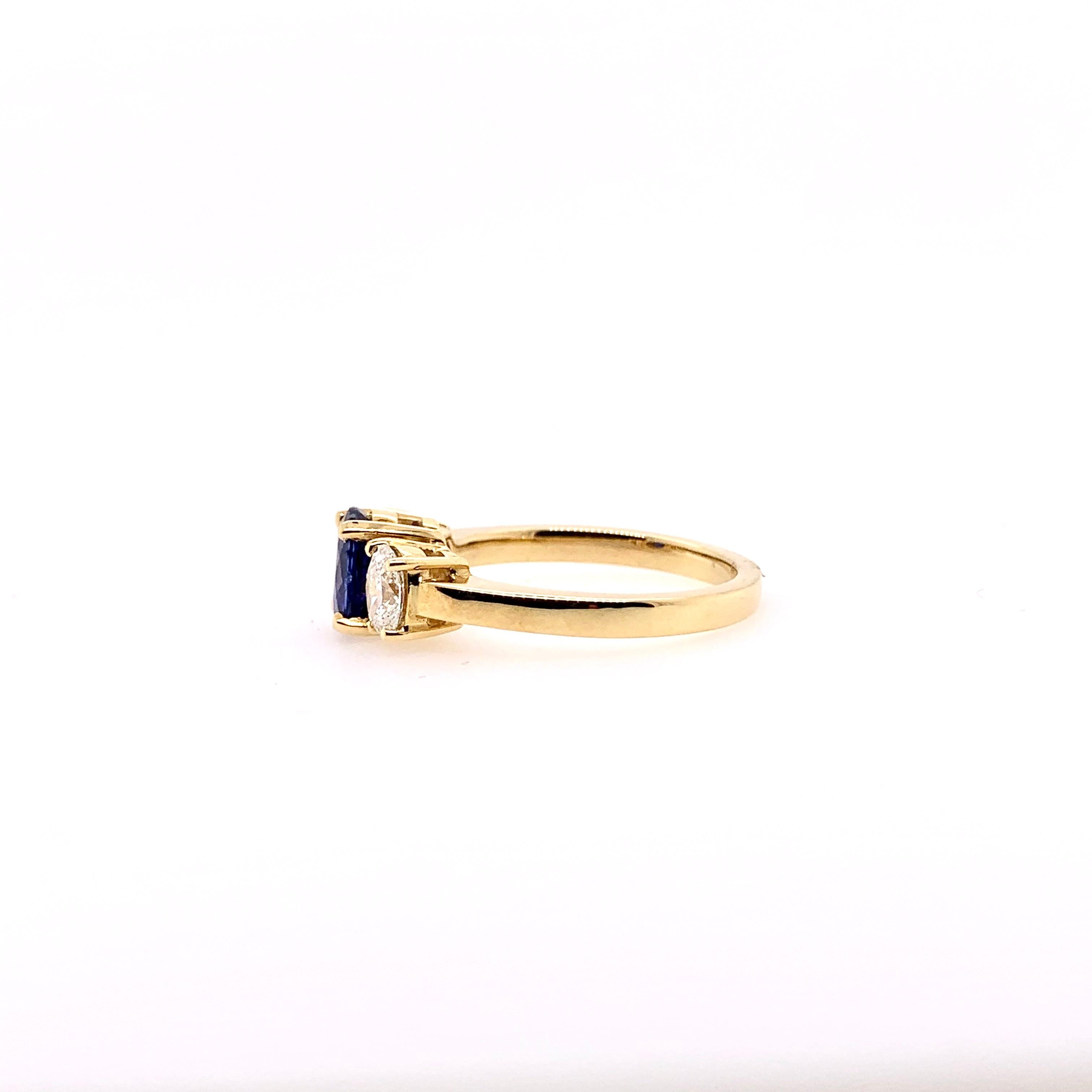 Ein klassischer Ring mit 3 blauen Saphiren und Diamanten in einer Fassung aus 18 Karat Gelbgold.  Der ovale blaue Saphir von 1,30 ct. hat atemberaubende blaue Farbtöne und wird von 2 ovalen Diamanten mit einem Gesamtgewicht von 0,61 ct. flankiert. 