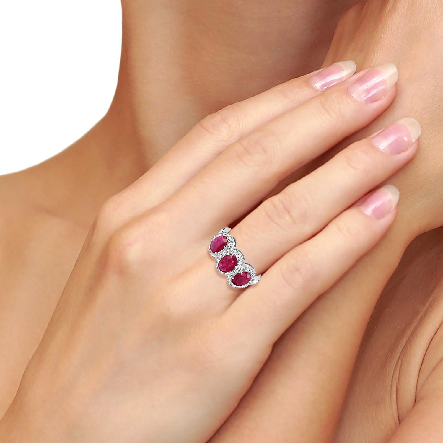 Réalisée en or blanc 18 carats, cette bague présente trois rubis du Mozambique richement colorés, sertis côte à côte et rehaussés de diamants étincelants le long de l'anneau. L'association d'un rouge vif et d'un blanc éclatant en fait un modèle à la