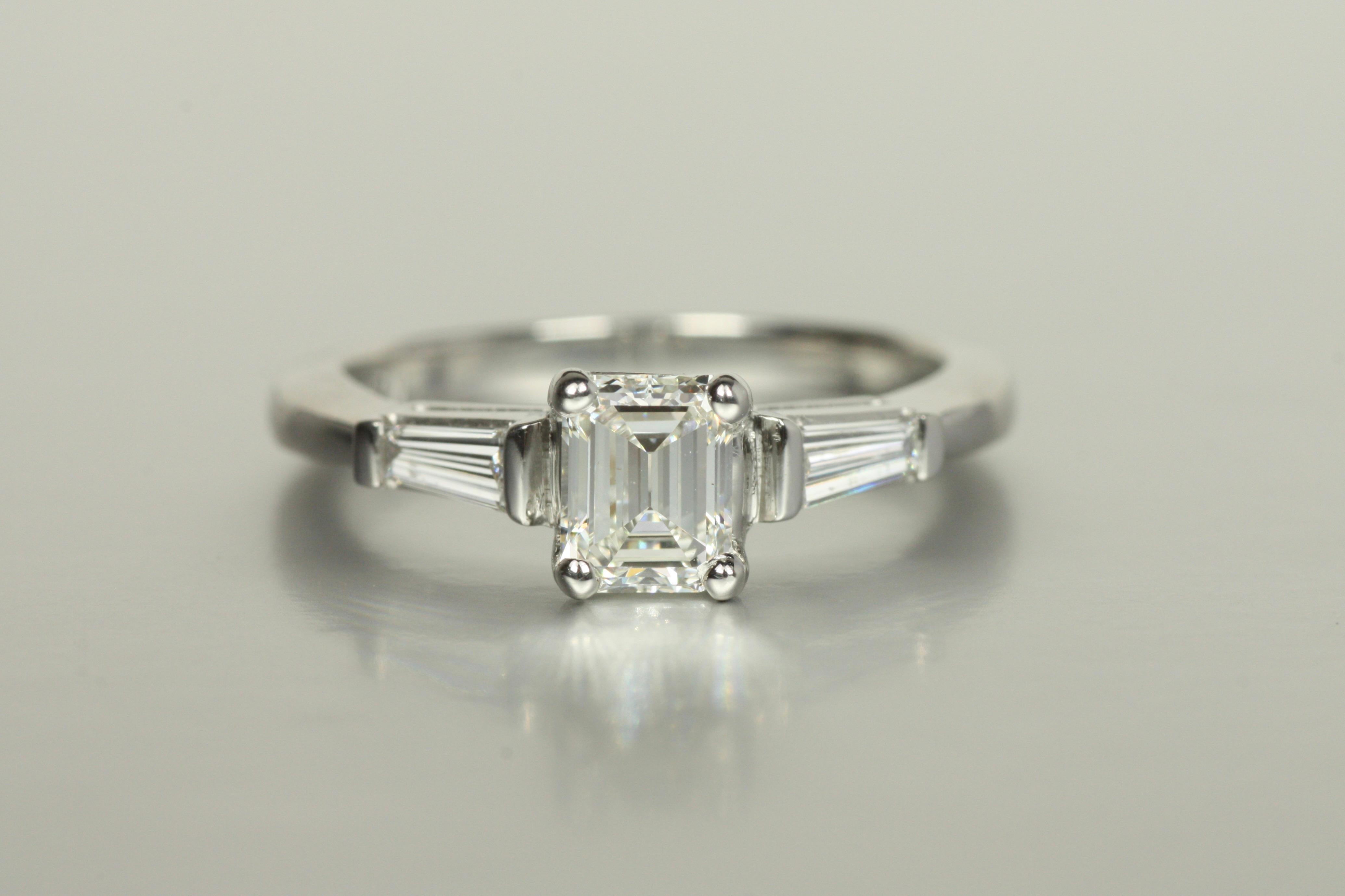 A true classic, this platinum 3-stone engagement ring exudes timeless sophistication. At its heart is a stunning 0.64ct emerald cut diamond, celebrated for its clean lines and remarkable clarity (VVS2). Flanked by two tapered baguette diamonds, this
