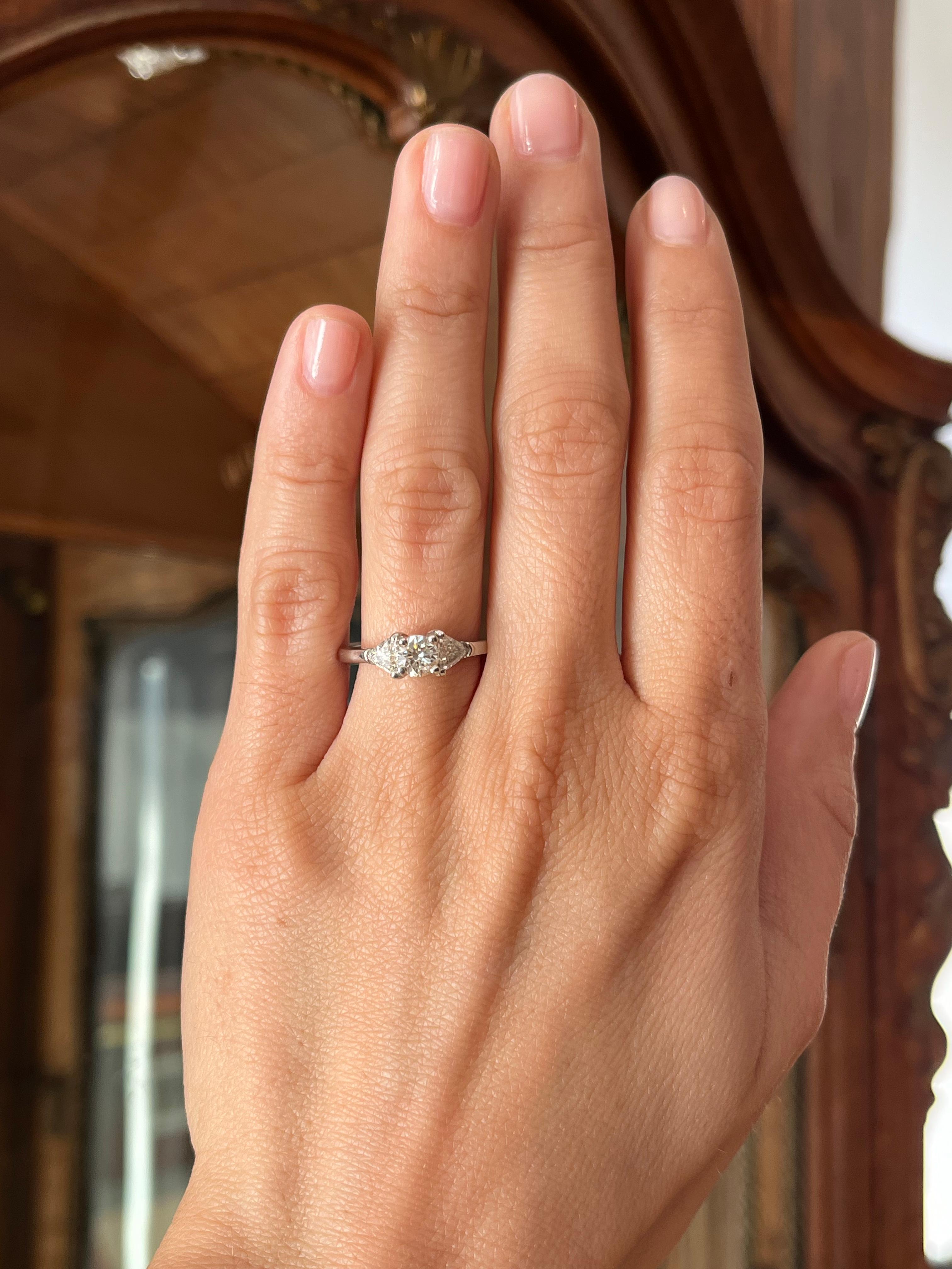 Ein klassischer Verlobungsring aus Platin mit drei Steinen, einem runden Diamanten im Brillantschliff von 0,45 ct. in der Mitte (Reinheit I1, verbesserte Reinheit, Farbe K) und zwei Diamanten im Dreiecksschliff, einer auf jeder Seite (0,60 ct.,
