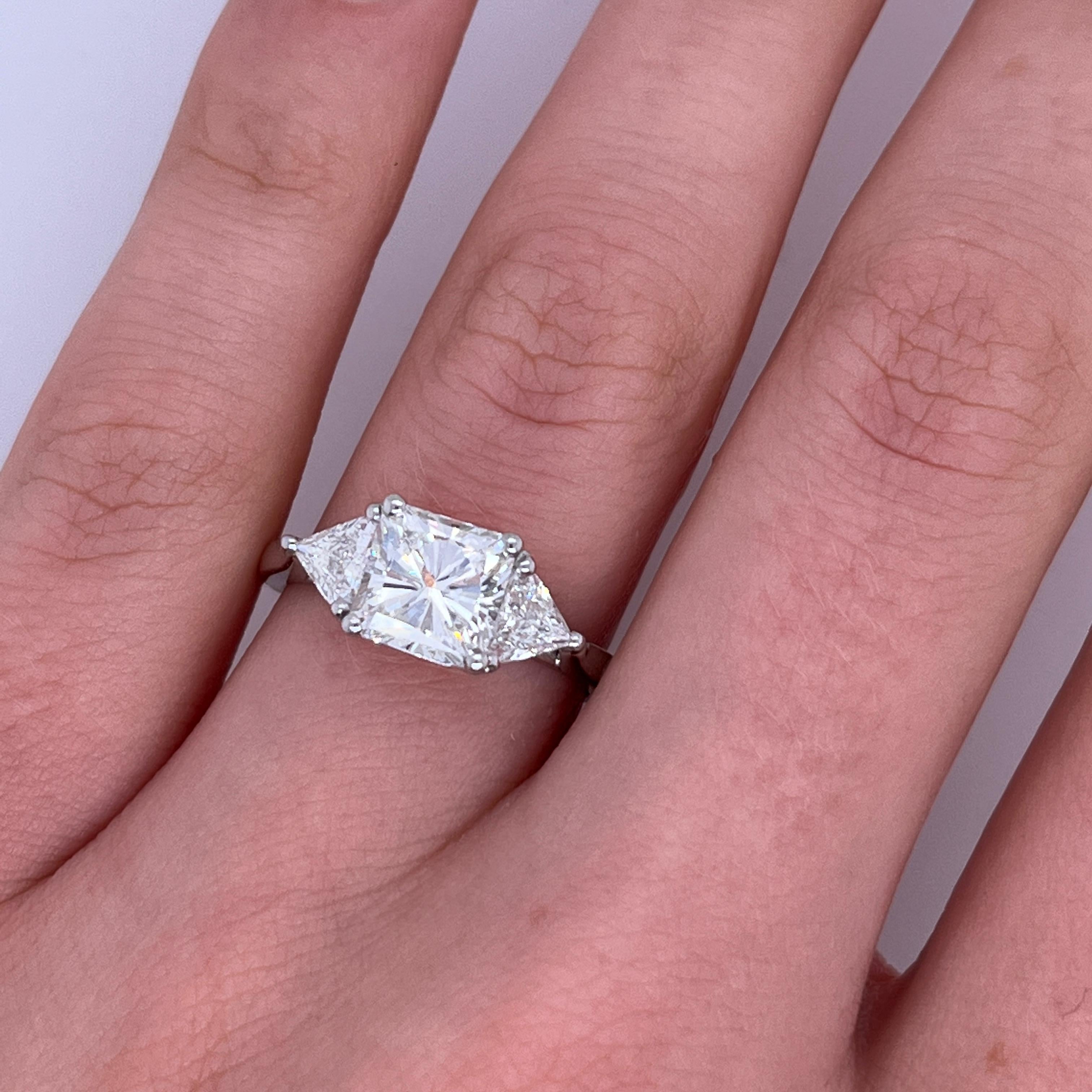 A breathtaking symbol of commitment, this three-stone engagement ring features a bold and modern 1.71ct princess cut diamond at its heart. 
Flanked by two matching triangle-cut diamonds on each side, the design beautifully blends geometric