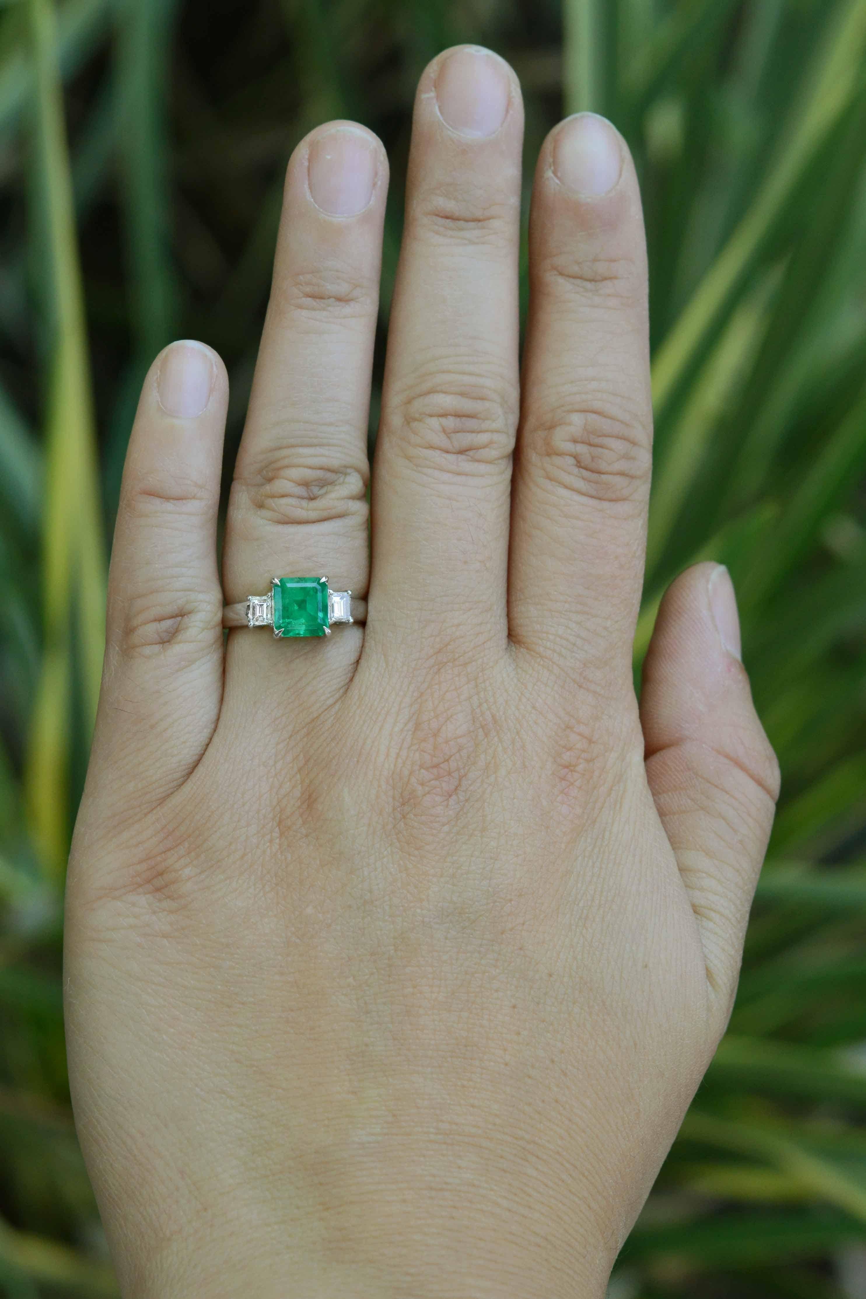 The focus of this 3 stone engagement ring is a bright green emerald with a vivid, internal glow presented with 2 spectacular emerald cut diamonds embracing either side. The glossy, polished platinum plays a huge part in this ring, contrasting the