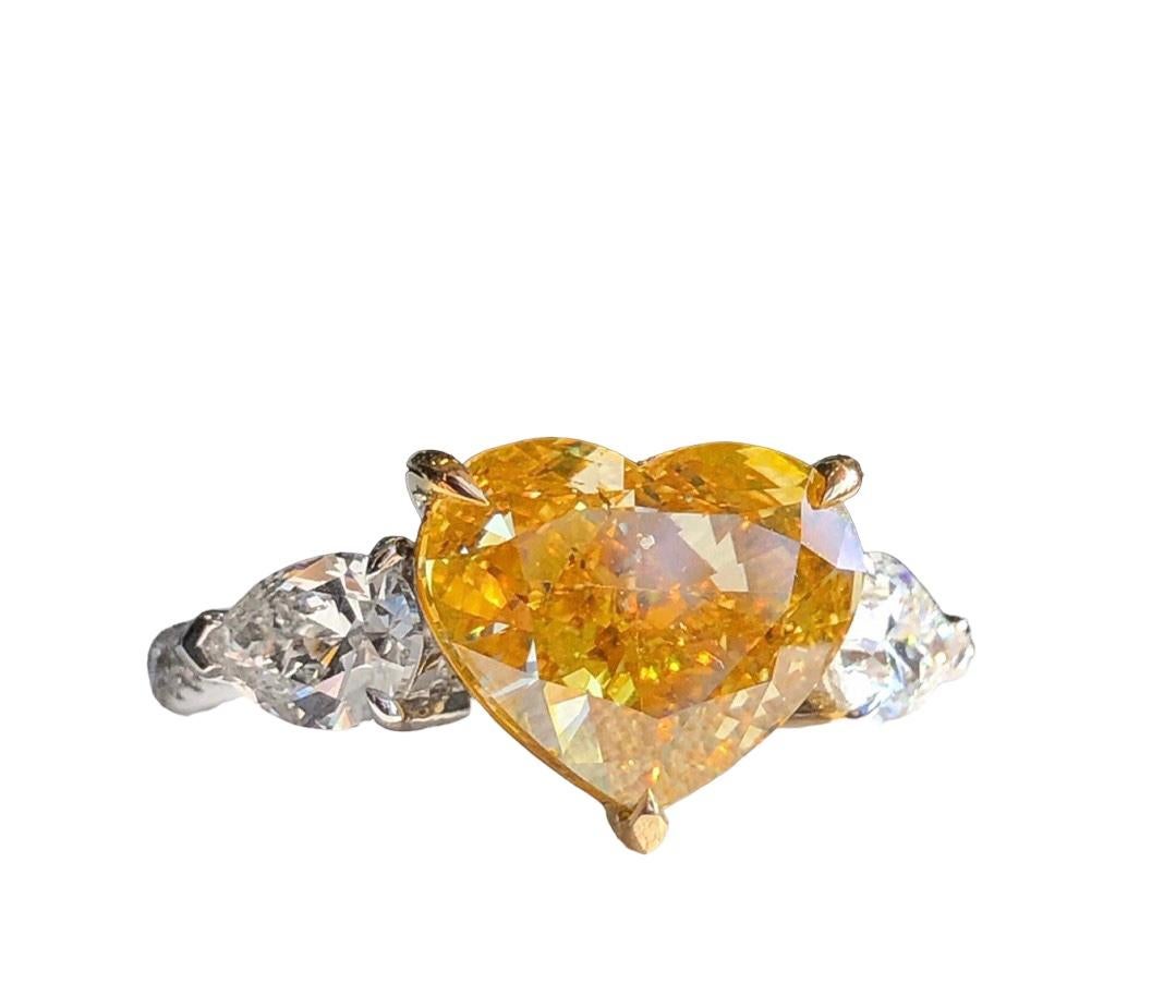 We invite you to discover this elegant and minimalist engagement ring set with a 5,02 carats GIA certified Fancy Deep Brownish Yellow Heart cut diamond accented of two colorless pear-cut diamonds, this 3 stone ring  is the ideal ring for a perfect