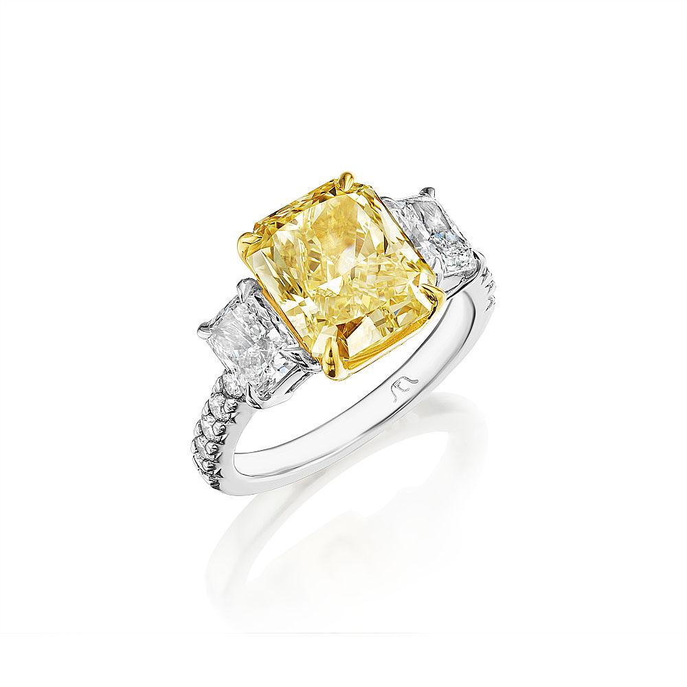 This beautiful and classic handmade ring showcases a GIA certified 4.49 carat radiant cut yellow diamond in the center, framed by two additional GIA certified radiant cut white diamond side stones weighing 1.41 carats, and 10 round brilliant cut