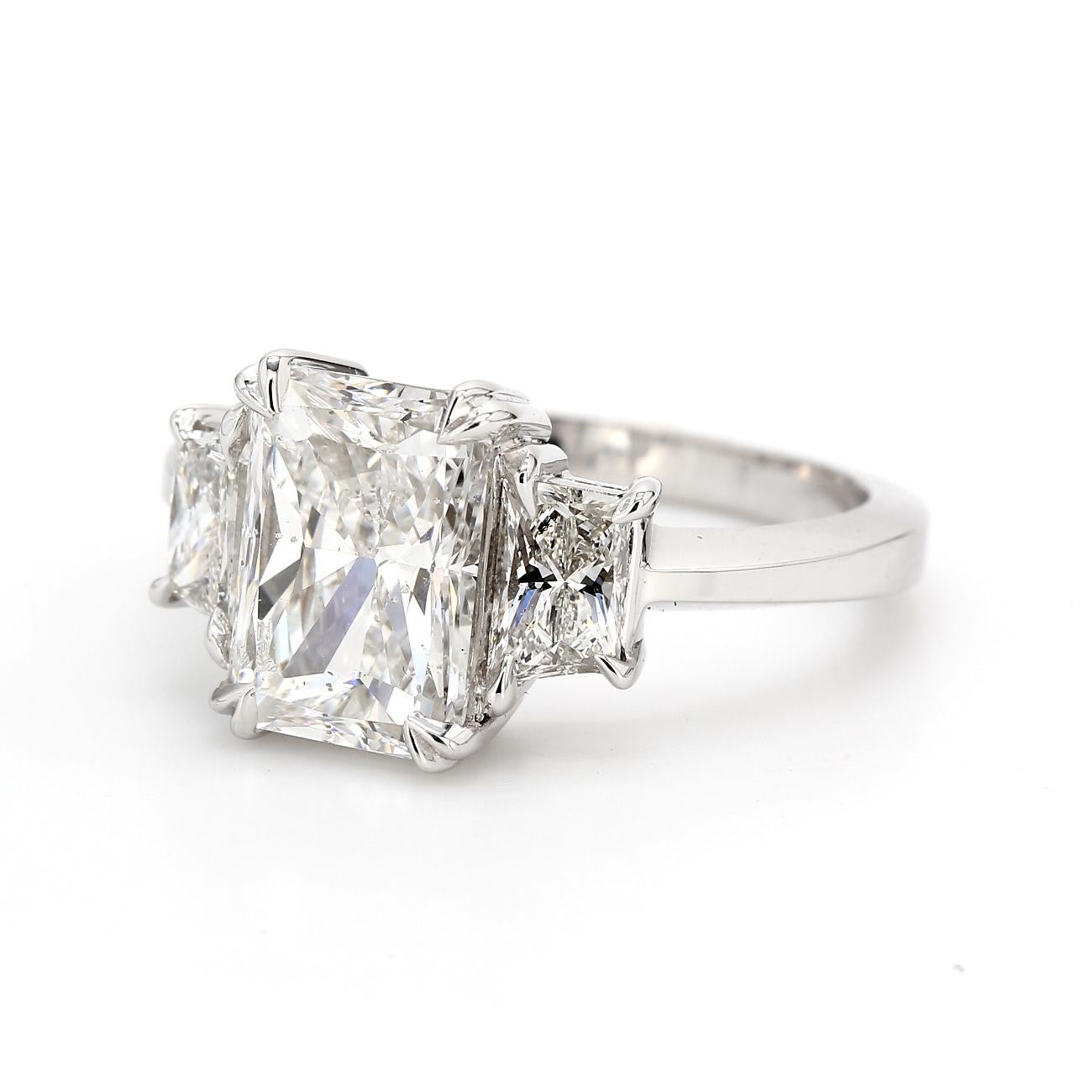 3-stone ring in platinum with GIA certified E/SI1 radiant cut center and prong set trapezoid diamond sides.  D3.84ct.t.w.  (Center - 3.01ct.)