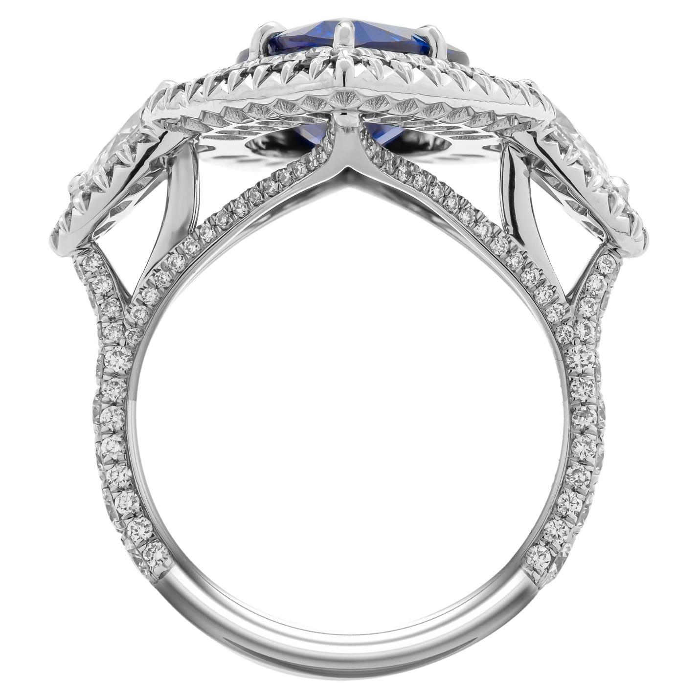3 stone ring in PT950 with blue sapphire
Double halo around center stone, with blue sapphires, diamond shank and halos around side stones; 
Side stones: 0.74 tcw G VS1
Center stone: 5.04 Sapphire Pear Shape GIA#2221376740
 Melee white: 1.25ct
 Melee