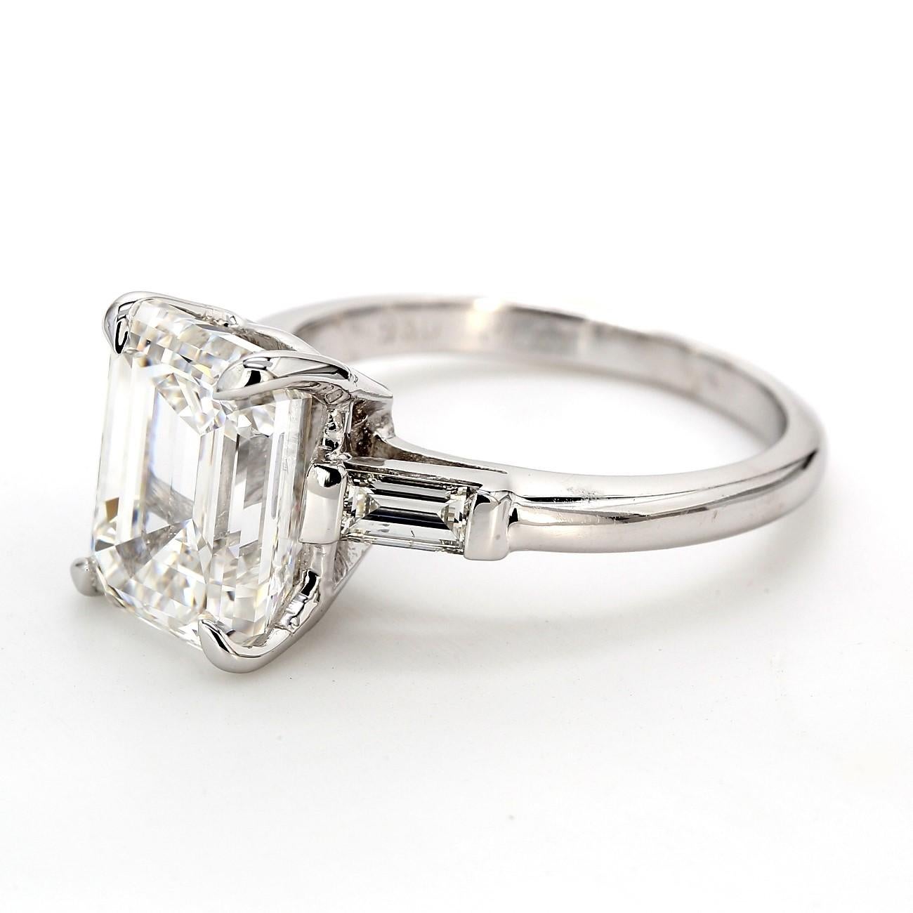 Anello a tre pietre in platino con pietra centrale taglio smeraldo certificata GIA F/SI1 e pietre laterali con diamanti baguette incastonati a canale.  D3.90ct.t.w.  (Centro - 3,51ct.)