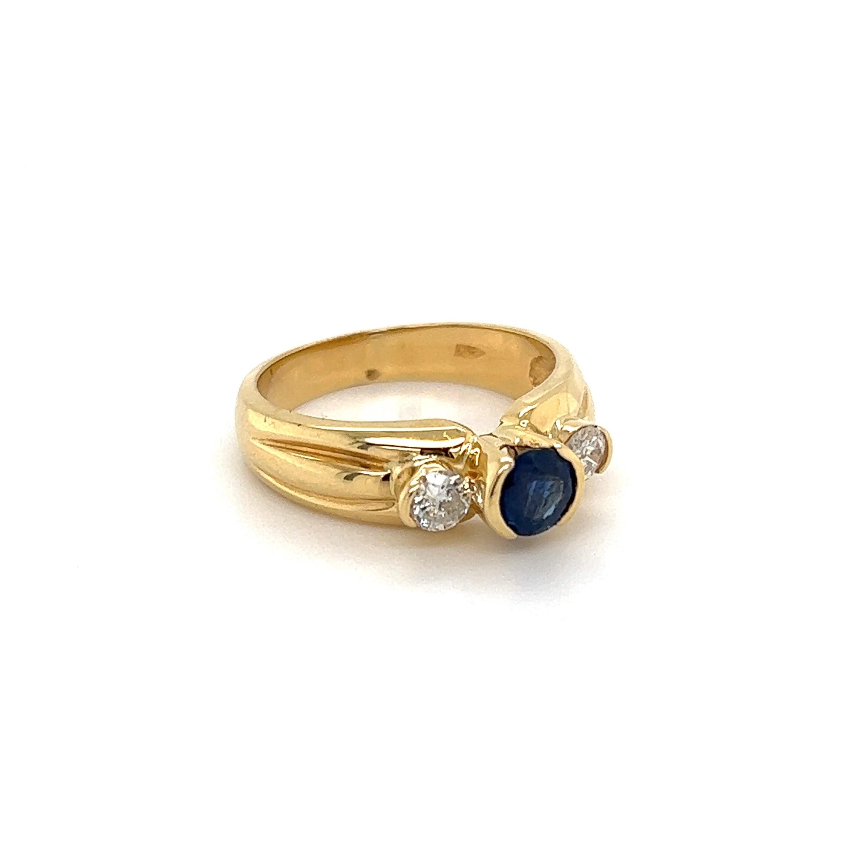 Beautiful finely detailed Gold Three-Stone Blue Sapphire and Diamond Trilogy Ring. Center securely nestled with a Hand set 0.50 Carat Round Sapphire and 2 Diamonds approx. 0.30tcw. Hand crafted 14K Yellow Gold mounting. Approx. dimensions: 0.98
