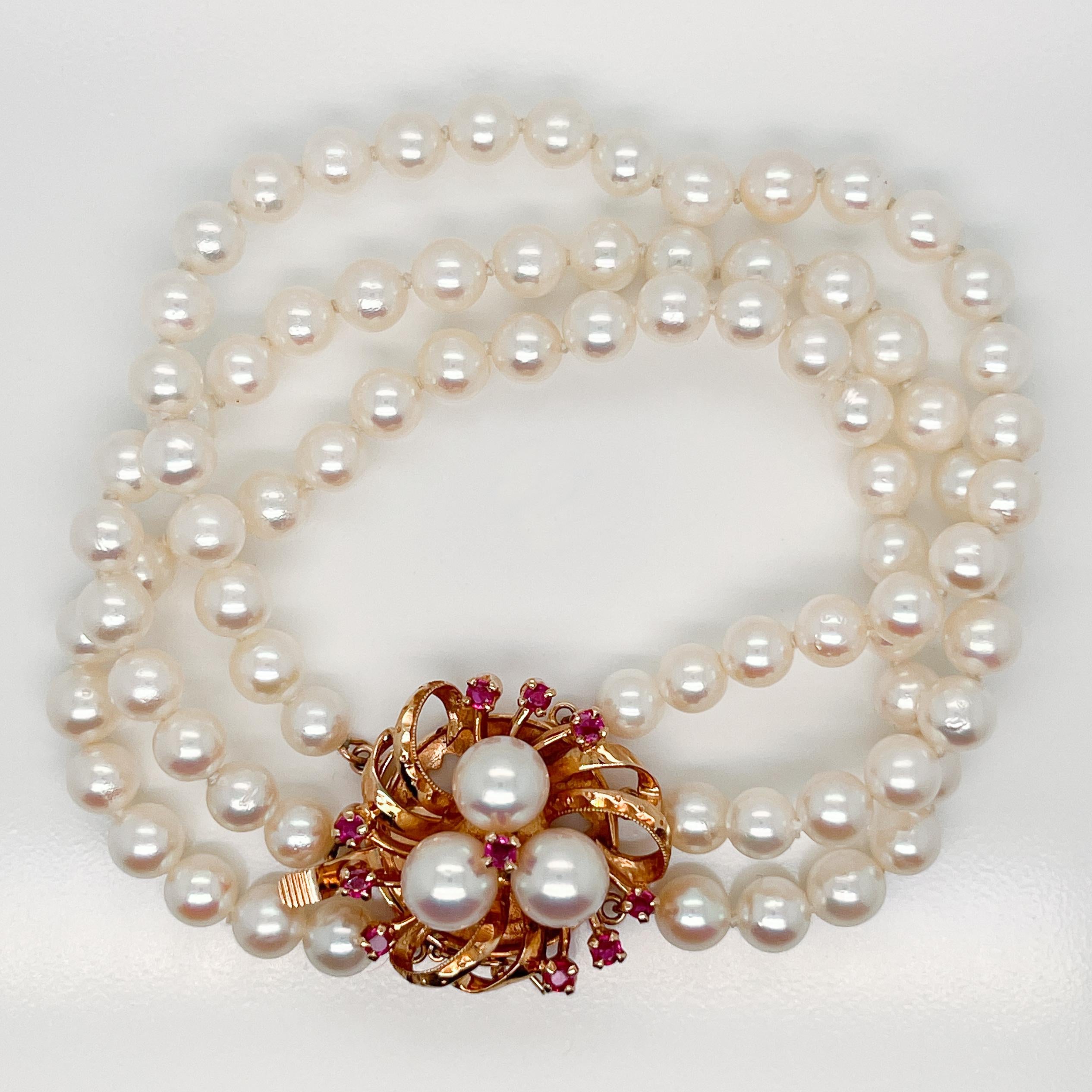 A very fine 3-strand Tasaki Akoya pearl bracelet with a 14k gold and ruby clasp.

With three strands of round white pearls hand knotted on silk cords. 

The flower shaped 14k gold box clasp is prong-set rubies.

Simply a wonderful bracelet!

Overall