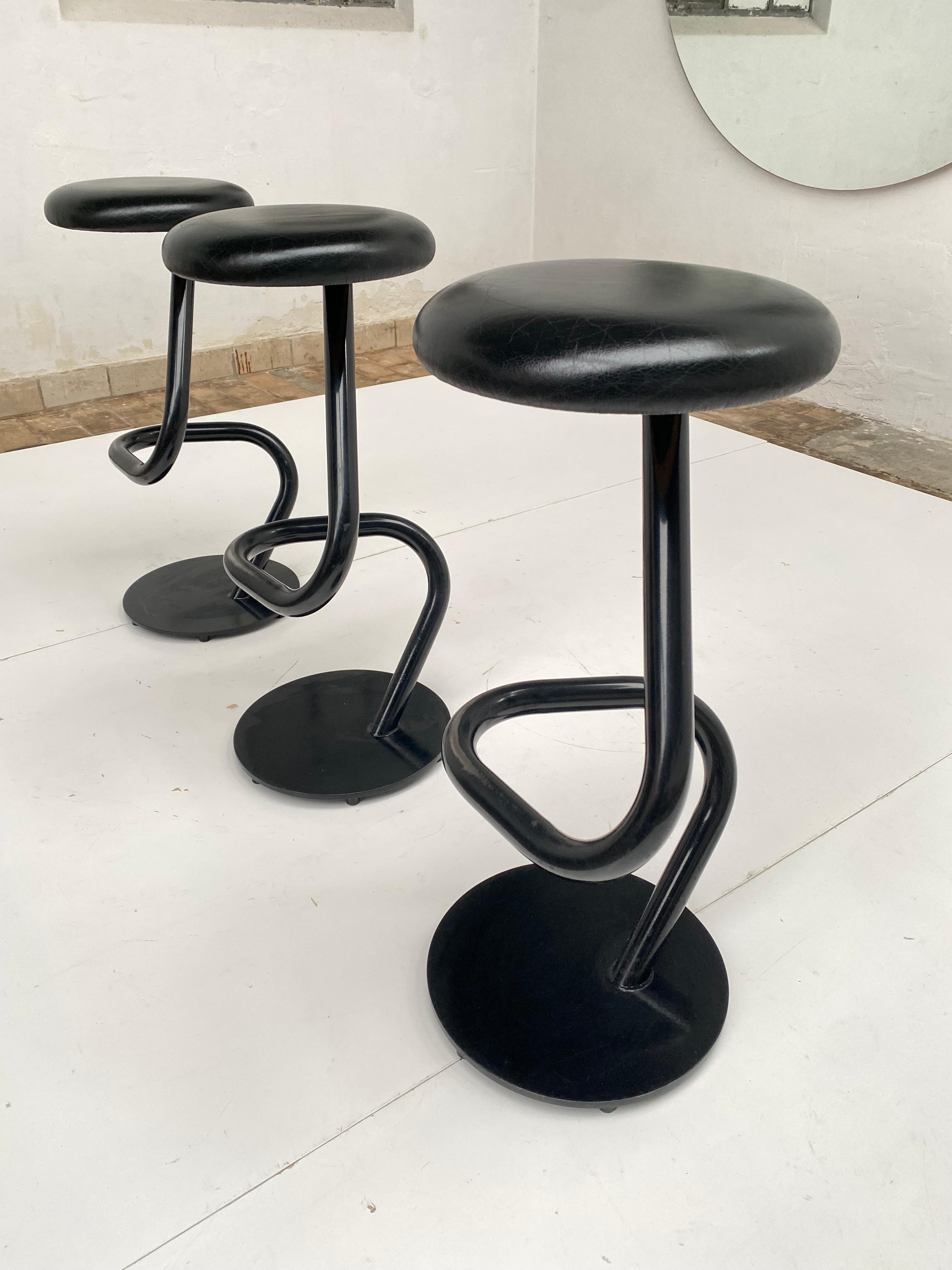 3 Sculptural Swiss post modern bar stools. 

Top quality Swiss Made in the 1980s.

Black Leather seat with a diameter of 34cm (13.38inch) on a heavy black enamelled steel base.

Genius and simple design with comfortable foot rest function on 2