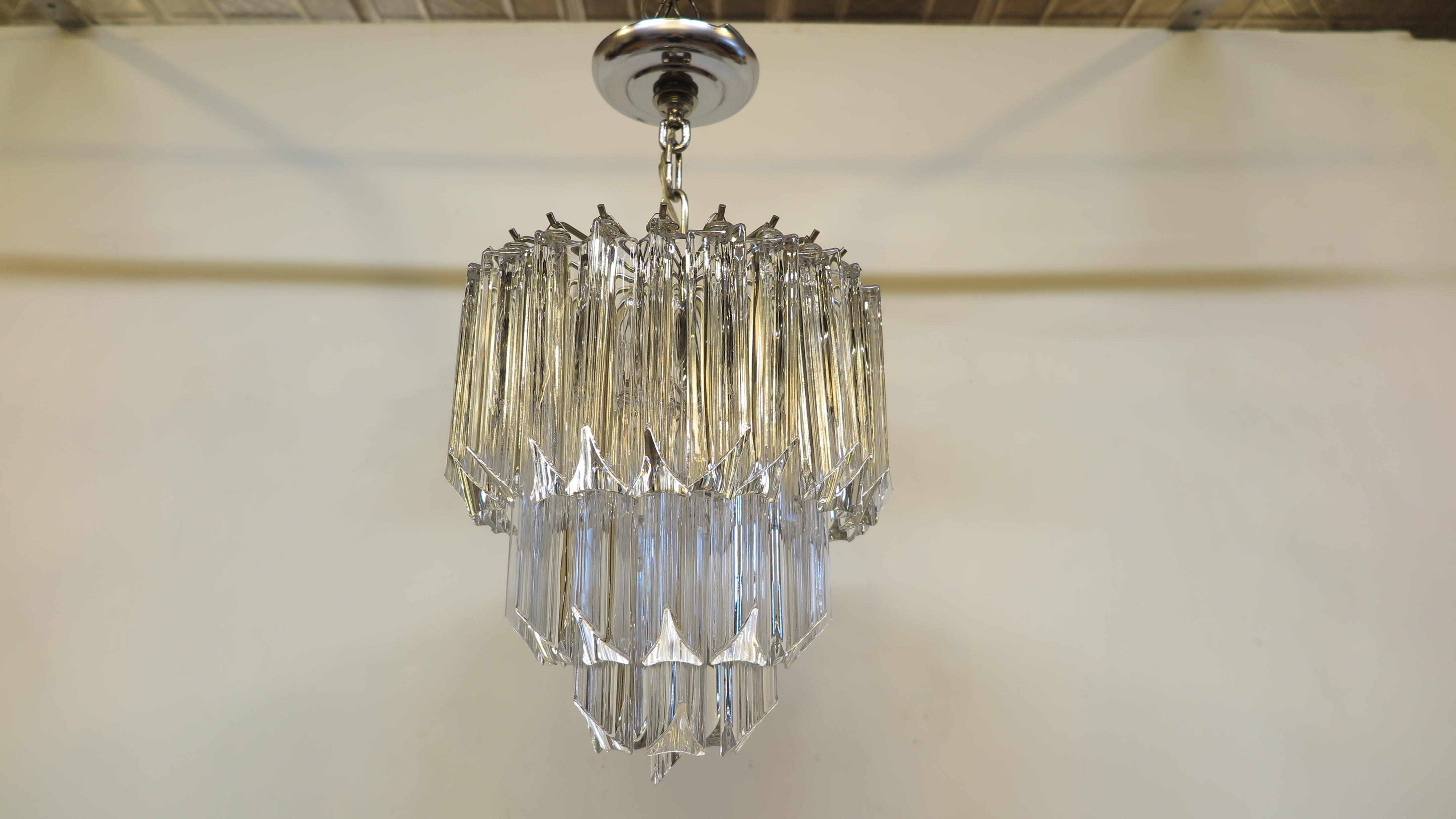 Beautiful glass prism chandelier in the style of Venini, circa 1970s. Having 3 tiers of hangers with 43 surrounding triedri glass prisms. Hanger frame is in nickel with 3 candelabra sockets. Of very good quality in good condition. Four glass prisms